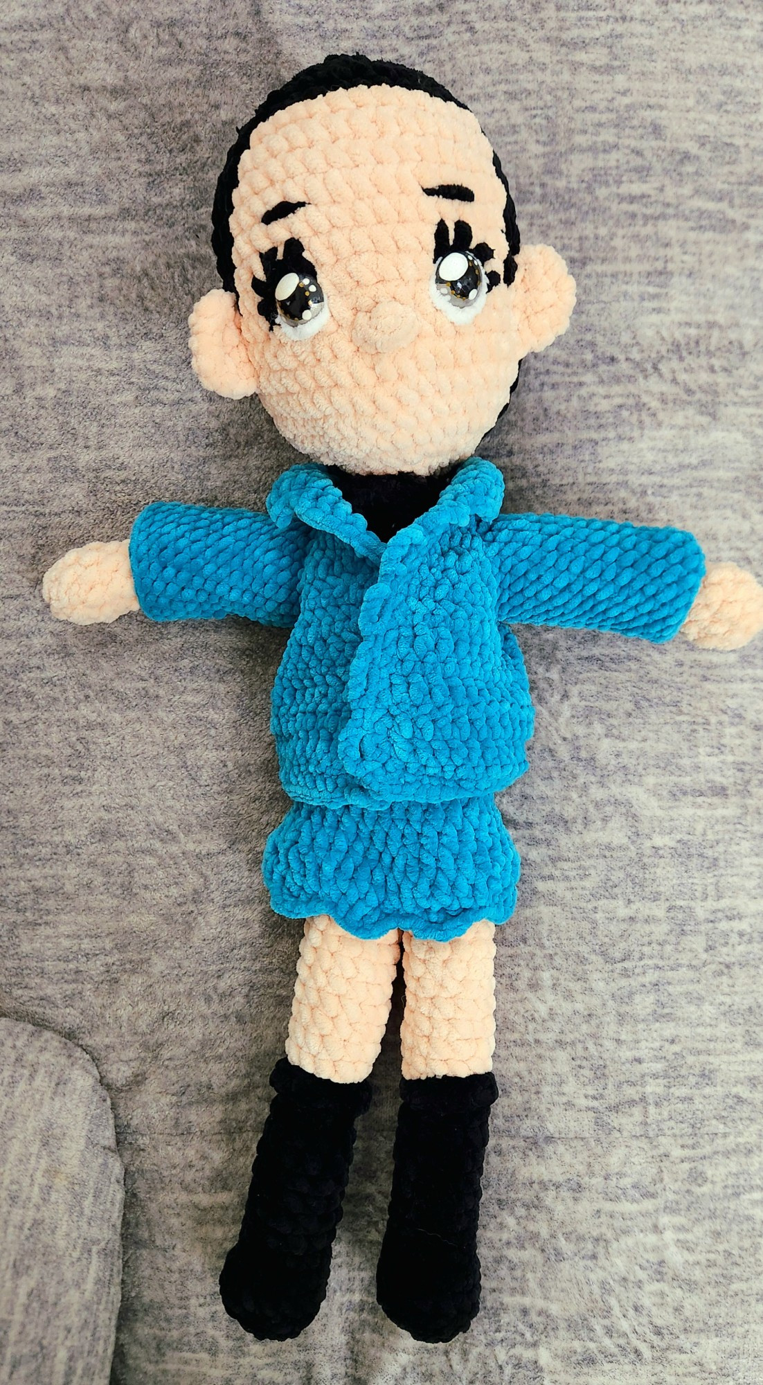 Pictured is a crochet plush. It is made out of black, cream, and teal yarn, with custom painted silver eyes. This doll is unfinished as the doll currently does not have hair.