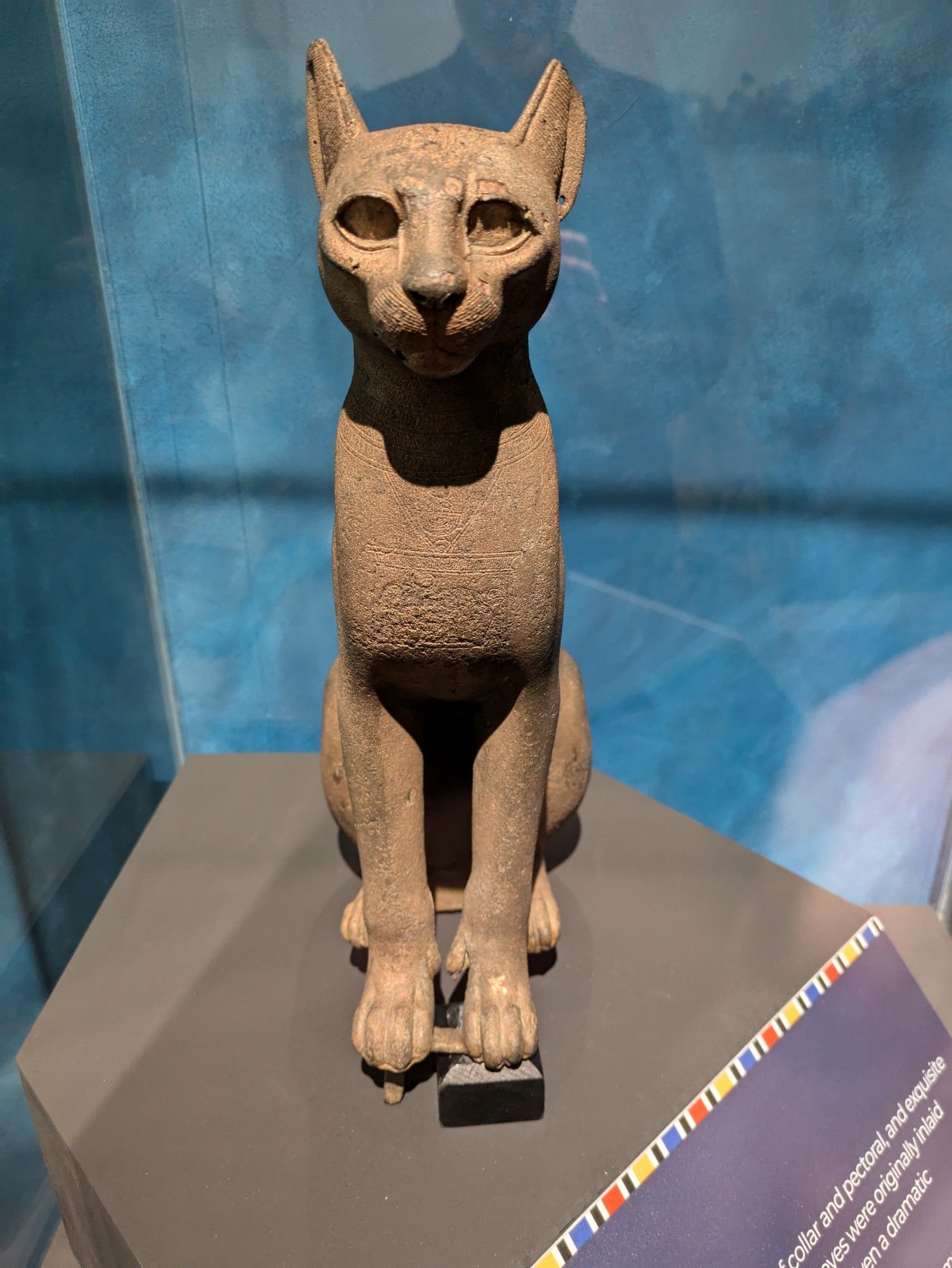 An Egyptian sculpture of a cat -the god Bastet, sitting up and looking at the viewer