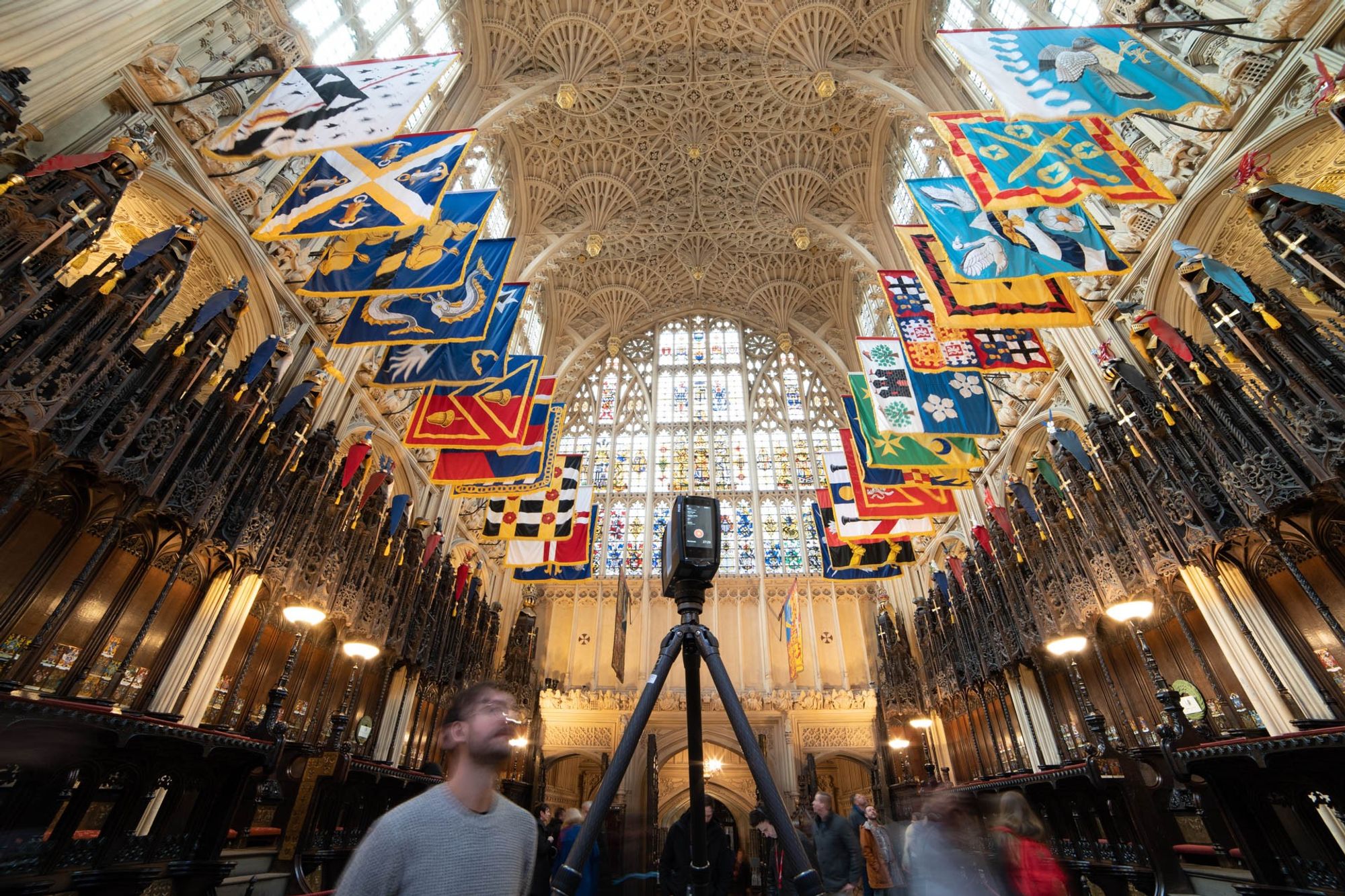 Academics scanning a medieval church's roof, with heraldic banners hanging down.