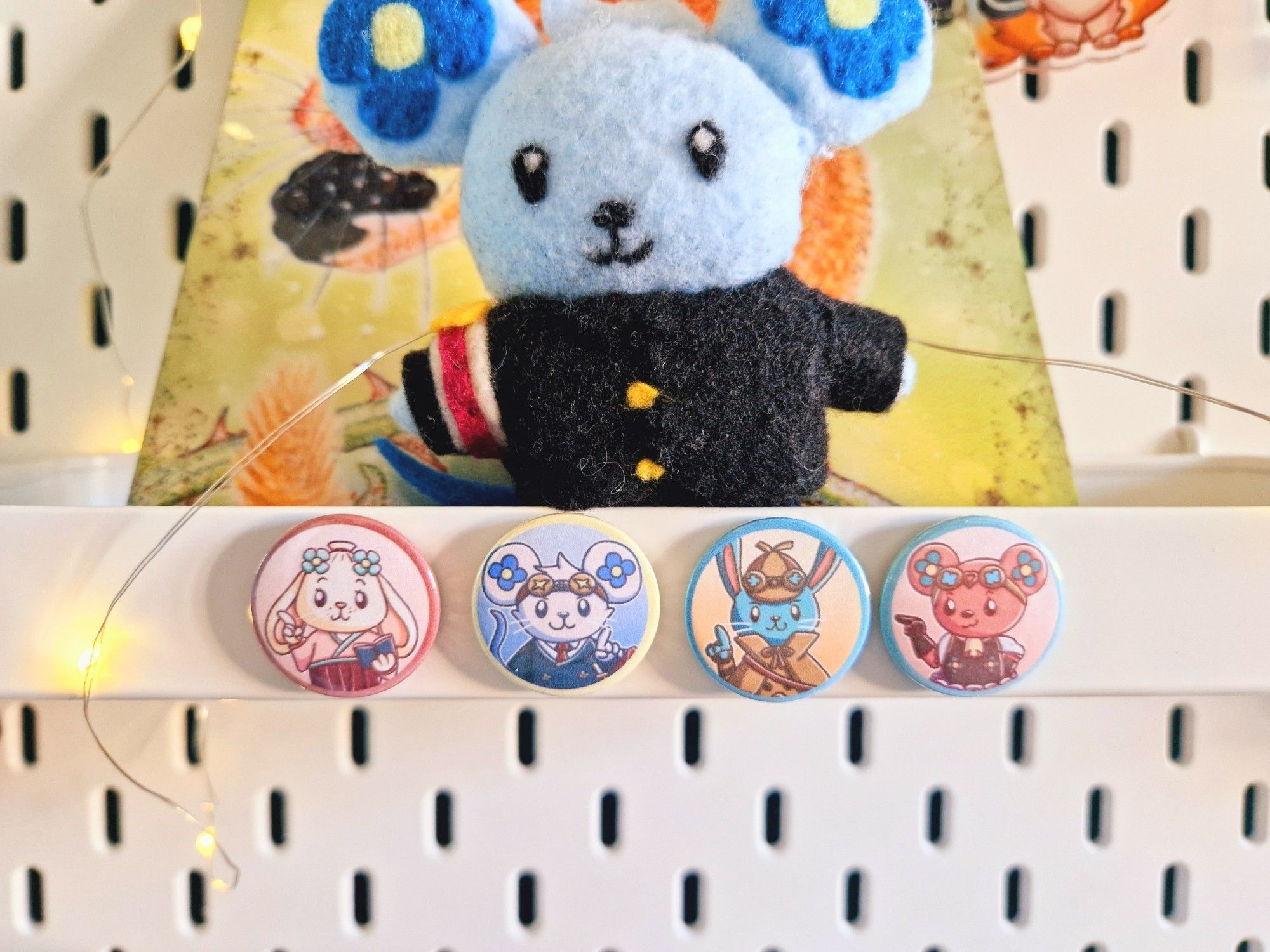 A photo of four little magnets on a shelf depicting the animal mascots of Susato, Ryunosuke (Chuunosuke), Herlock Sholmes, and Iris from The Great Ace Attorney Chronicles. A Chuunosuke made of felt stands on the shelf behind them.