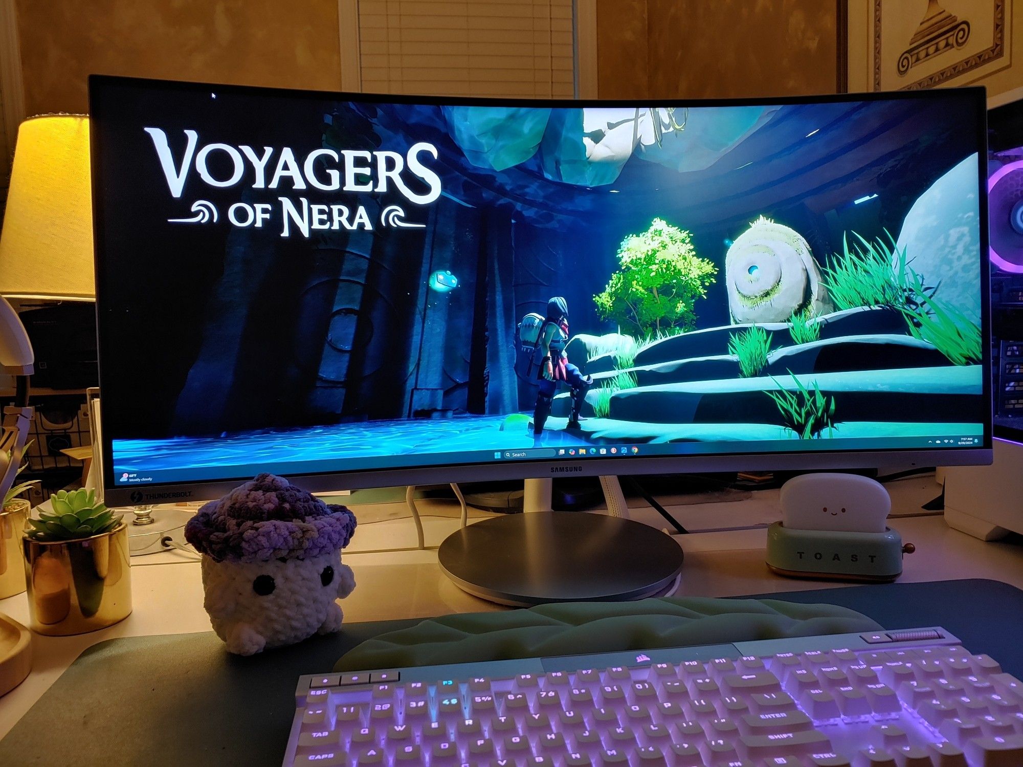 Photo of a PC monitor with a screenshot from the Voyagers of Nera playtest. The screenshot shows a character in an underground cavern looking at a stone obelisk covered in grass and small trees. There is light shining down from a vine covered hole above the obelisk. Shallow clear blue water covers the stone floor and a small ancient stone mask floats just behind the character.