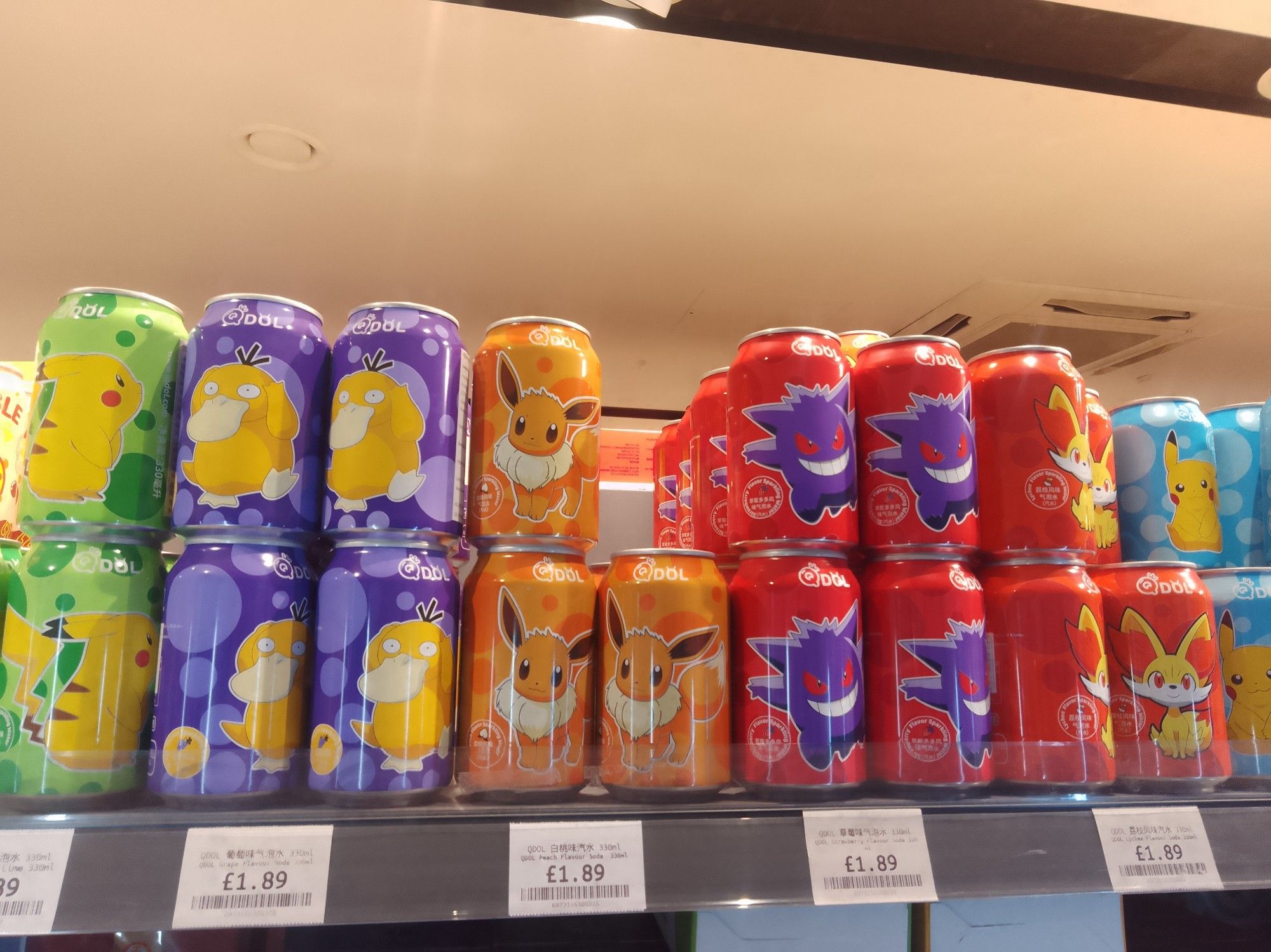 A row of brightly coloured cans of Pokémon-themed soda. Left to right is Pikachu, Psyduck, Eevee, Gengar, someone I don't recognise and Pikachu again. They are all priced at £1.89 each