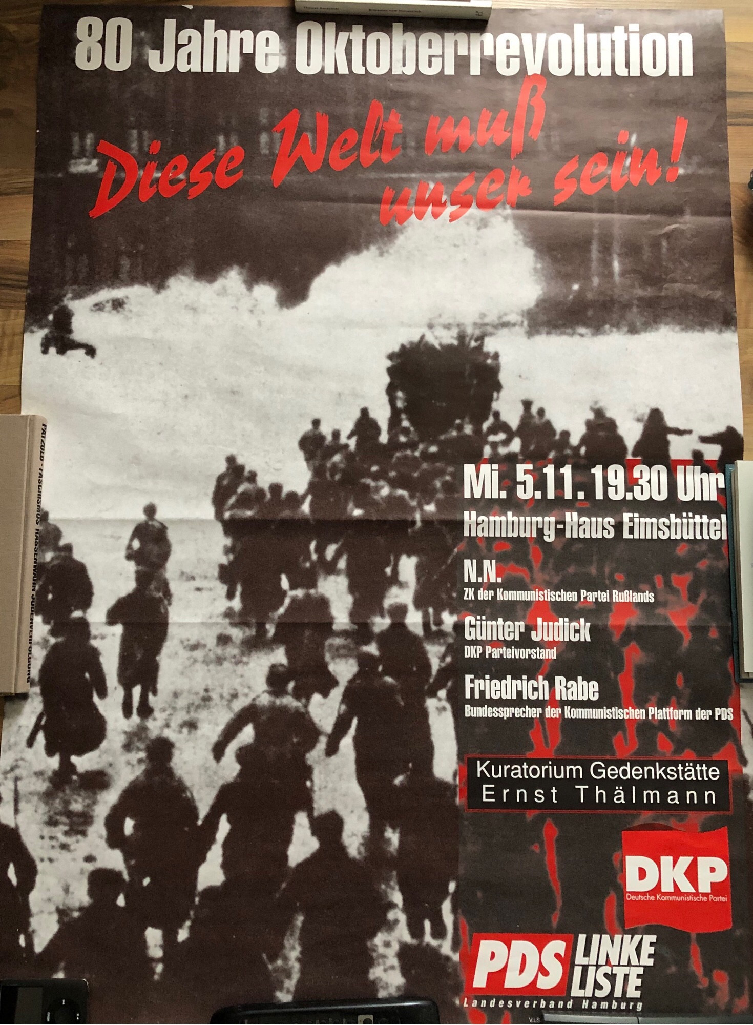 Plakat von DKP & PDS für eine Veranstaltung zum 80. Jubiläum der Oktoberrevolution, Hamburg 1997. Der Titel: “80 Jahre Oktoberrevolution - Diese Welt muss unser sein!”
Abgebildet sind die Informationen zur Veranstaltung wie Datum, Adresse und diverse eingeladene Redner & Gastsprecher, sowie die Logos der jeweiligen Organisatoren darunter die KPD, PDS Landesverband Hamburg und das Kuratorium Gedenkstätte Ernst Thälmann.