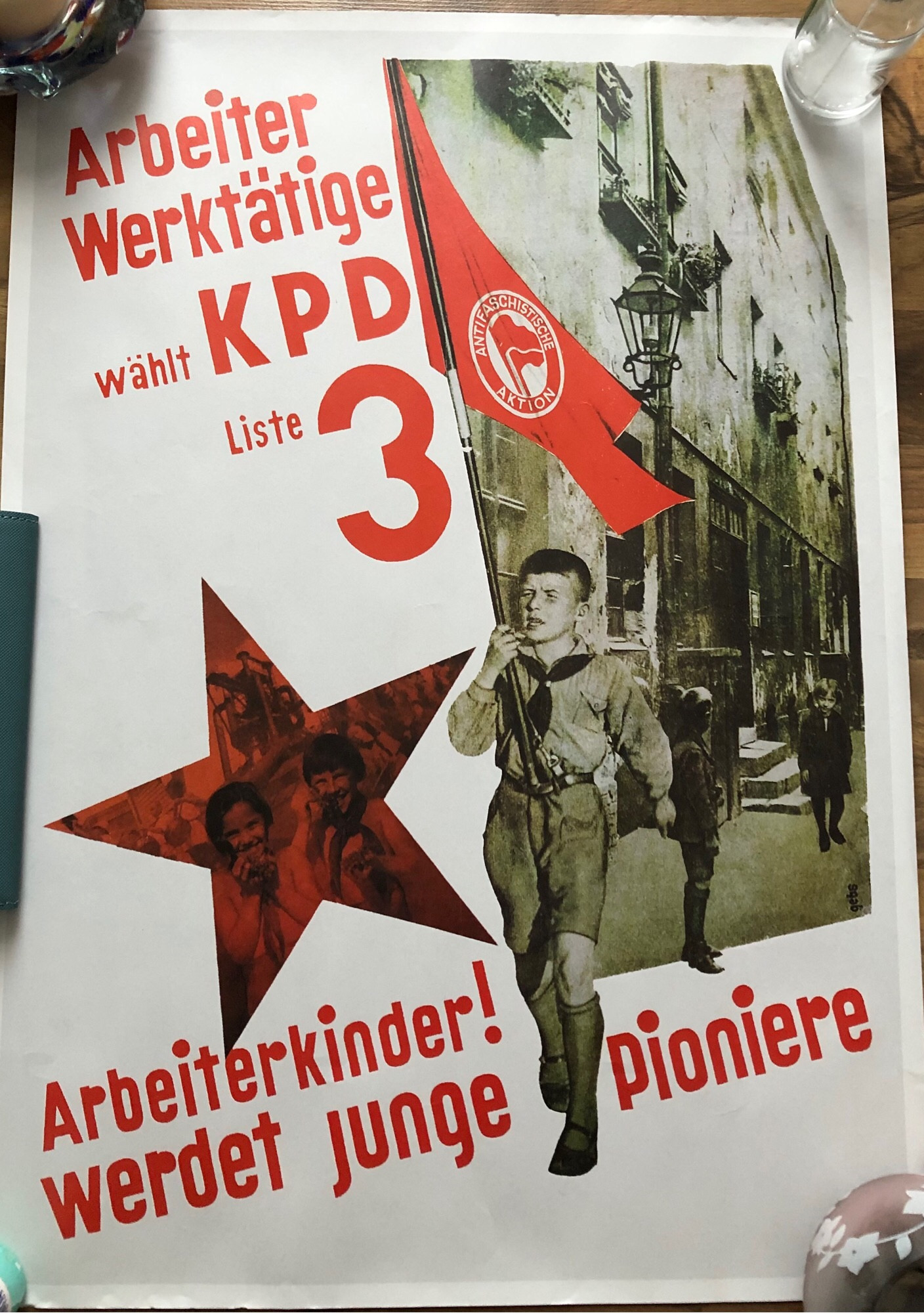 Wahlplakat der KPD, 1932. 
“Arbeiter, Werktätige wählt KPD Liste 3.
Arbeiterkinder! Werdet junge Pioniere”
Abgebildet ist ein Jungpionier der marschierend eine Standarte der Antifaschistischen Aktion trägt. Neben ihm, in einem roten Stern abgebildet: weitere Jungpioniere. 