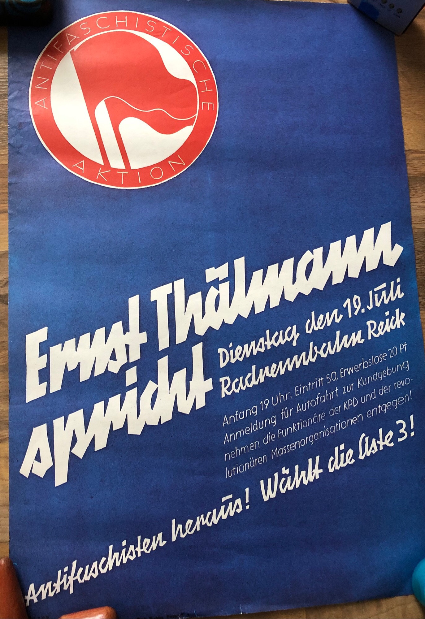 Plakat welches eine Rede von Ernst Thälmann für den 19. Juli 1932 in Dresden-Reick im Zuge des Wahlkampfs bewirbt.
Das Plakat ist tiefblau mit weißer Schrift, in der Ecke oben links ist das Symbol der Antifaschistischen Aktion (2 rote Fahnen auf weißem Grund in einem roten Kreis) abgebildet.
“ Ernst Thälmann spricht. Dienstag den 19. Juli 1932, Radrennbahn Reick. Anfang 19 Uhr, Eintritt 50, Erwerbslose 20pf. Anmeldung für Autofahrt zur Kundgebung nehme die Funktionäre der KPD und der revolutionäre Massenorganisationen entgegen!
Antifaschisten heraus! Wählt Liste 3!”