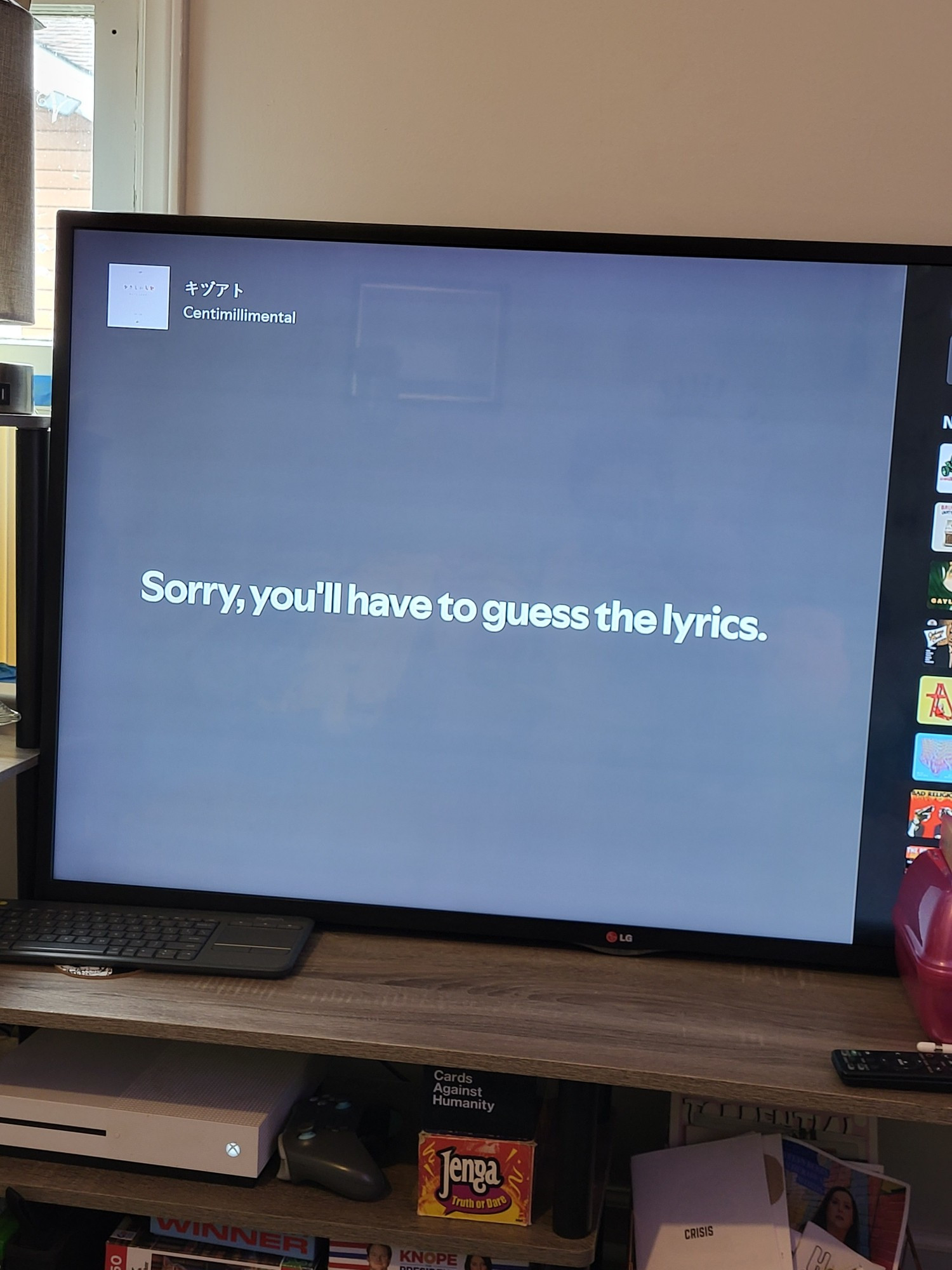 A picture of a television screen showing the Now Playing on the Spotify app. Centimillimental - Kizuato is playing, but the title of the song is written in kanji. The screen reads "sorry, you'll have to guess the lyrics" where lyrics would typically be provided