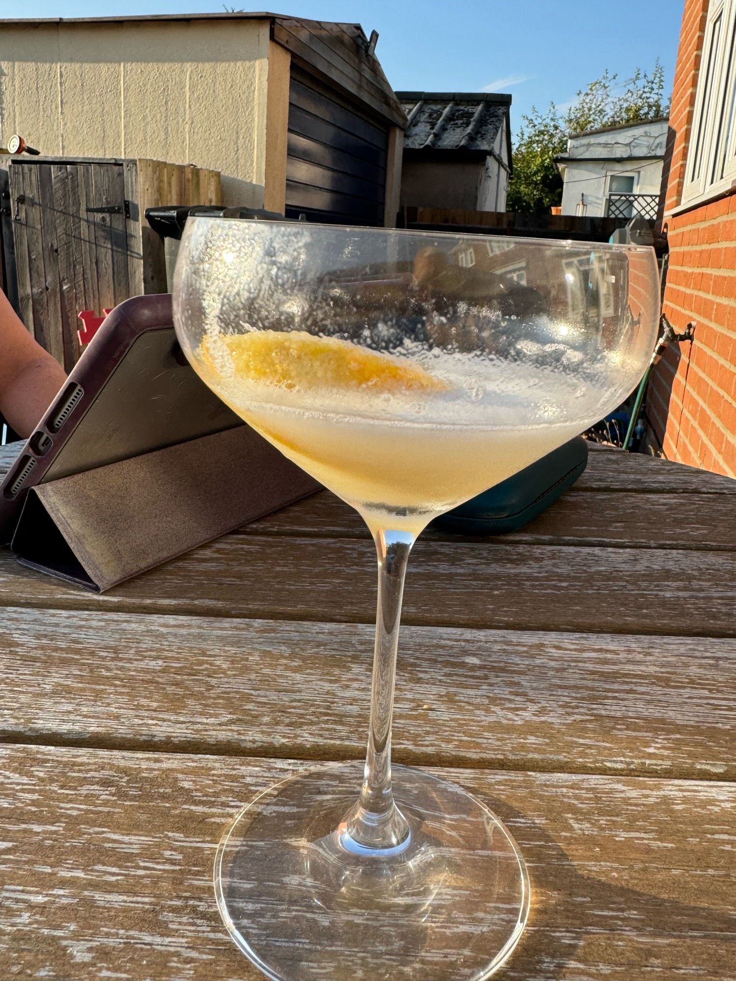 Glass of cocktail on wooden table. Cocktail is 1oz vodka, 3 oz of Prosecco and 4oz lemon sorbet.