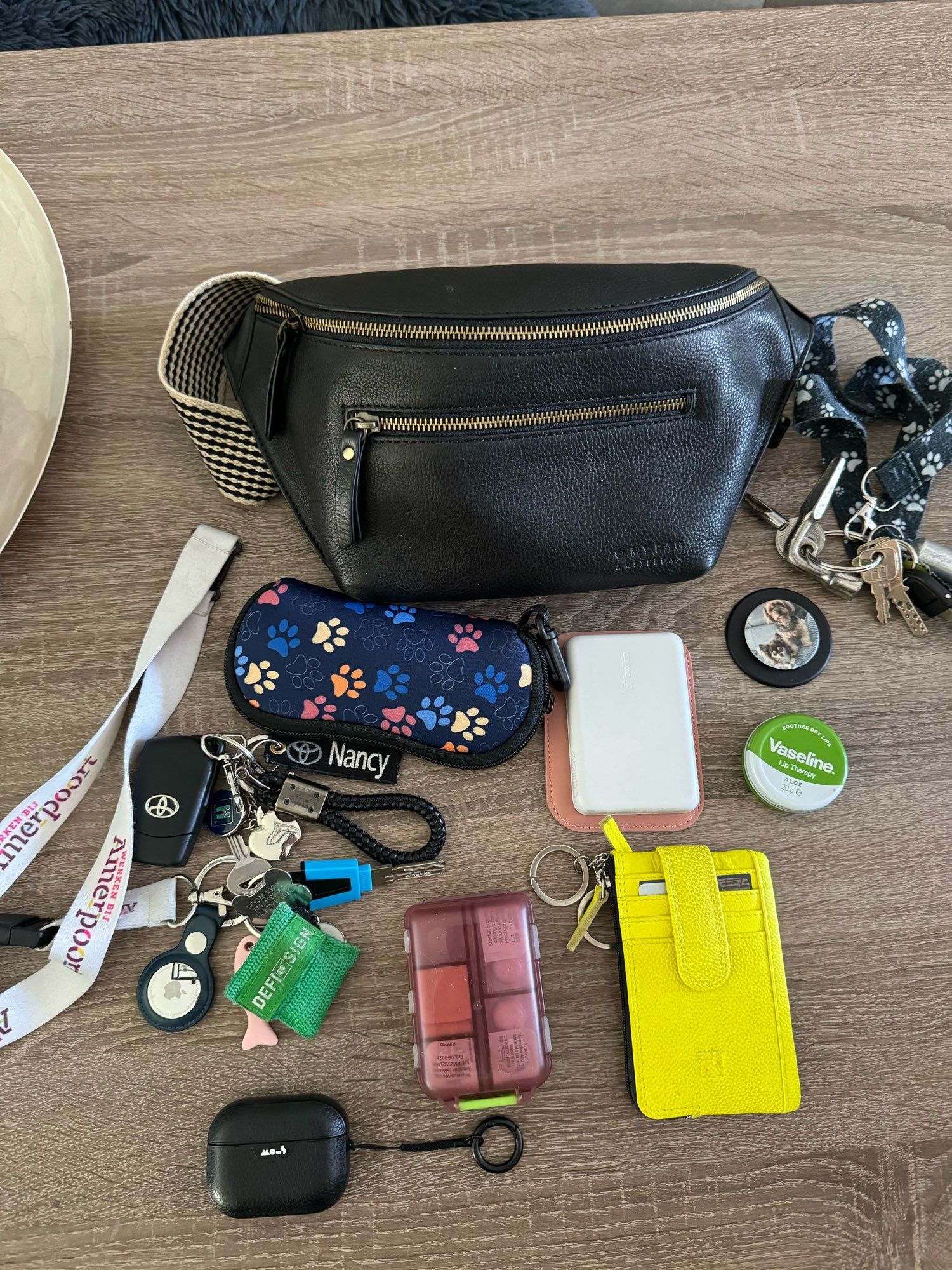 *airpods pro 2 
*pasjes/ kleingeld mapje van gerecycleerde politie kleding. 
*werksleutels 
*vasaline lipcare 
*medicijnen doosje met de nodige pillen
*leesbril in koker met pootjes 
*popsocket 
*autosleutel 
*huissleutel 
*bumbag van o my bag Amsterdam