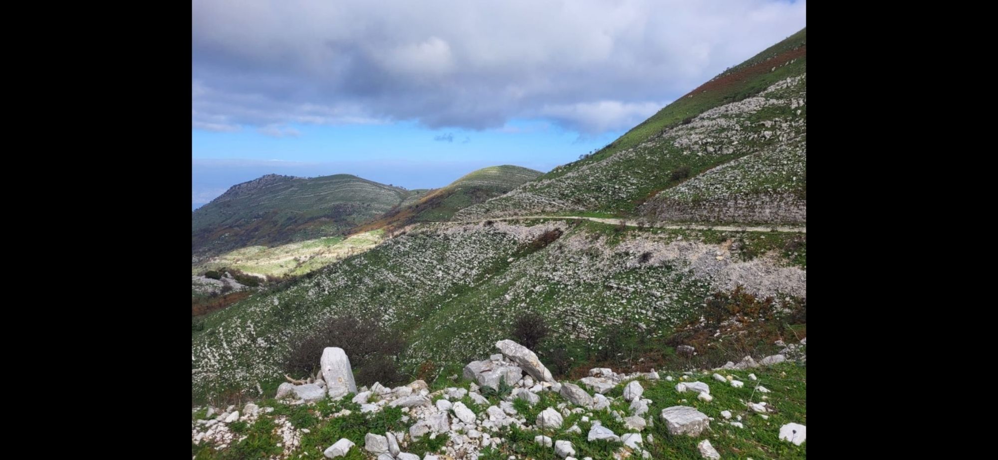 Sentier s'éloignant à flanc de montagne, petits rochers et végétation basse