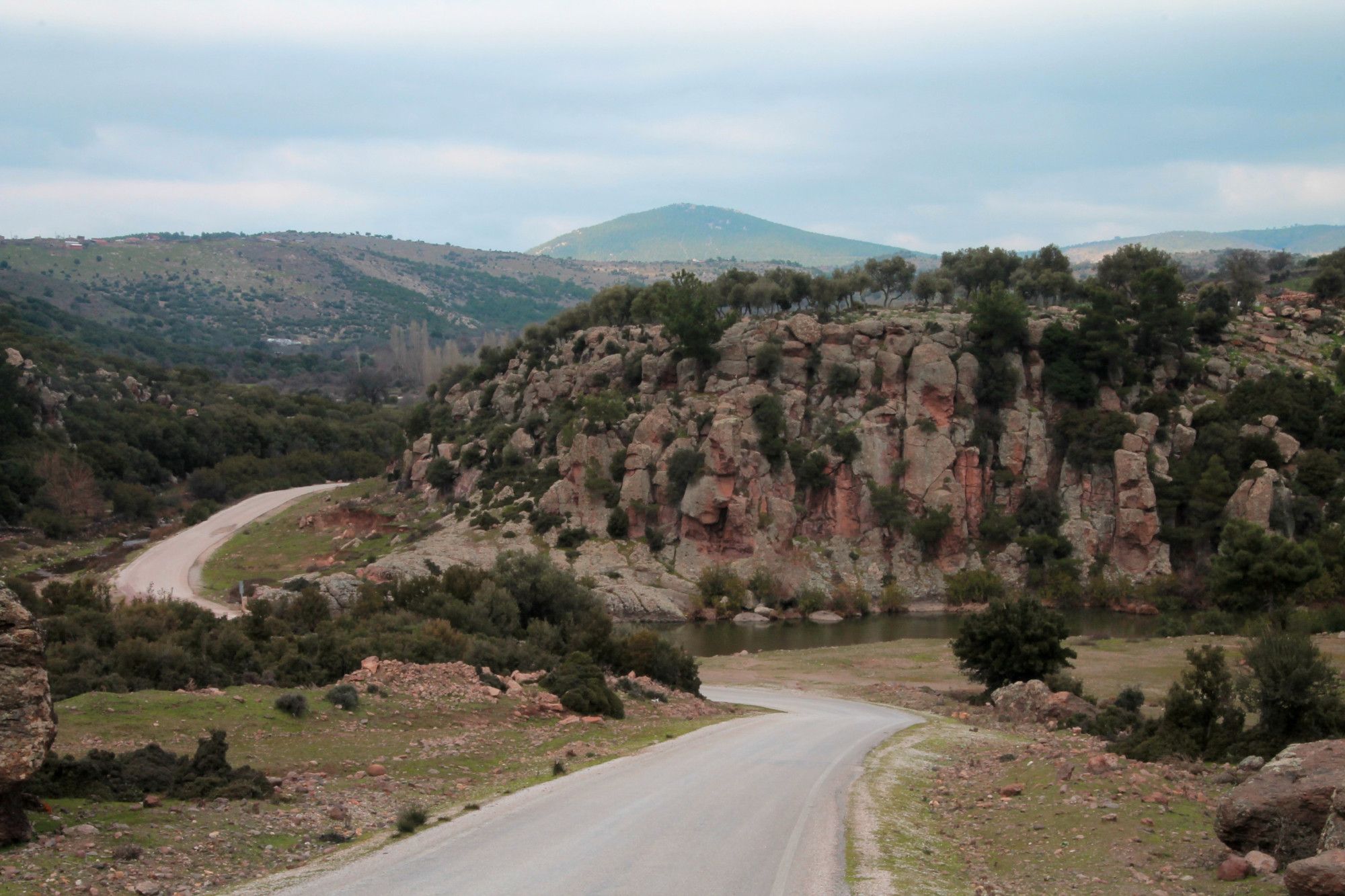 route serpentant dans paysage de falaises et montagnes, cours d'eau