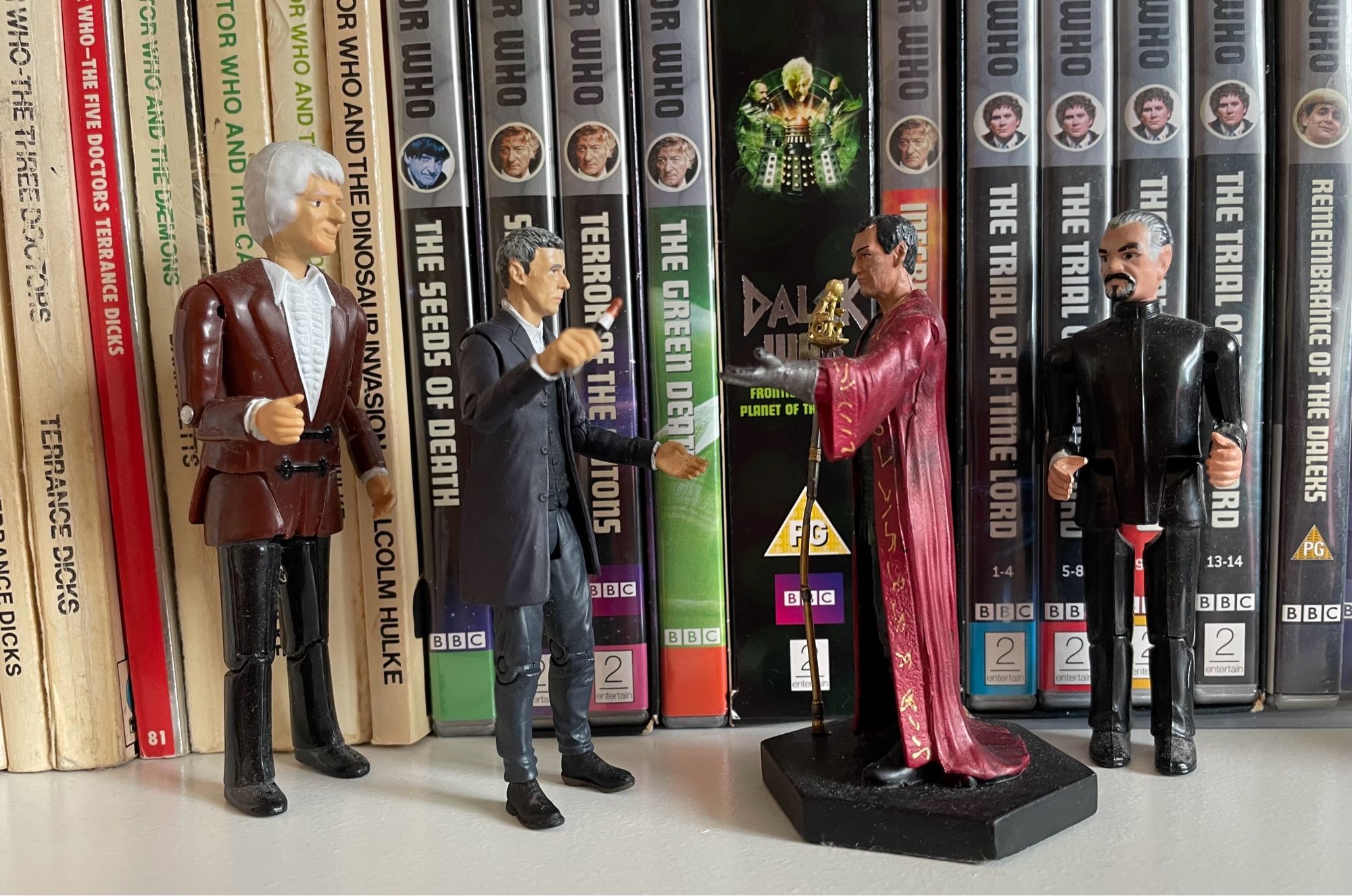 Toy figures of the 12th Doctor and Rassilon face off. A older Palitoy figures of the 3rd Doctor and the Master back them up.