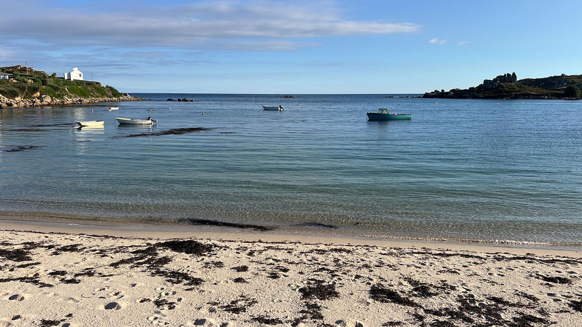 Photo of beach with turquoise waters and small boats in a bay