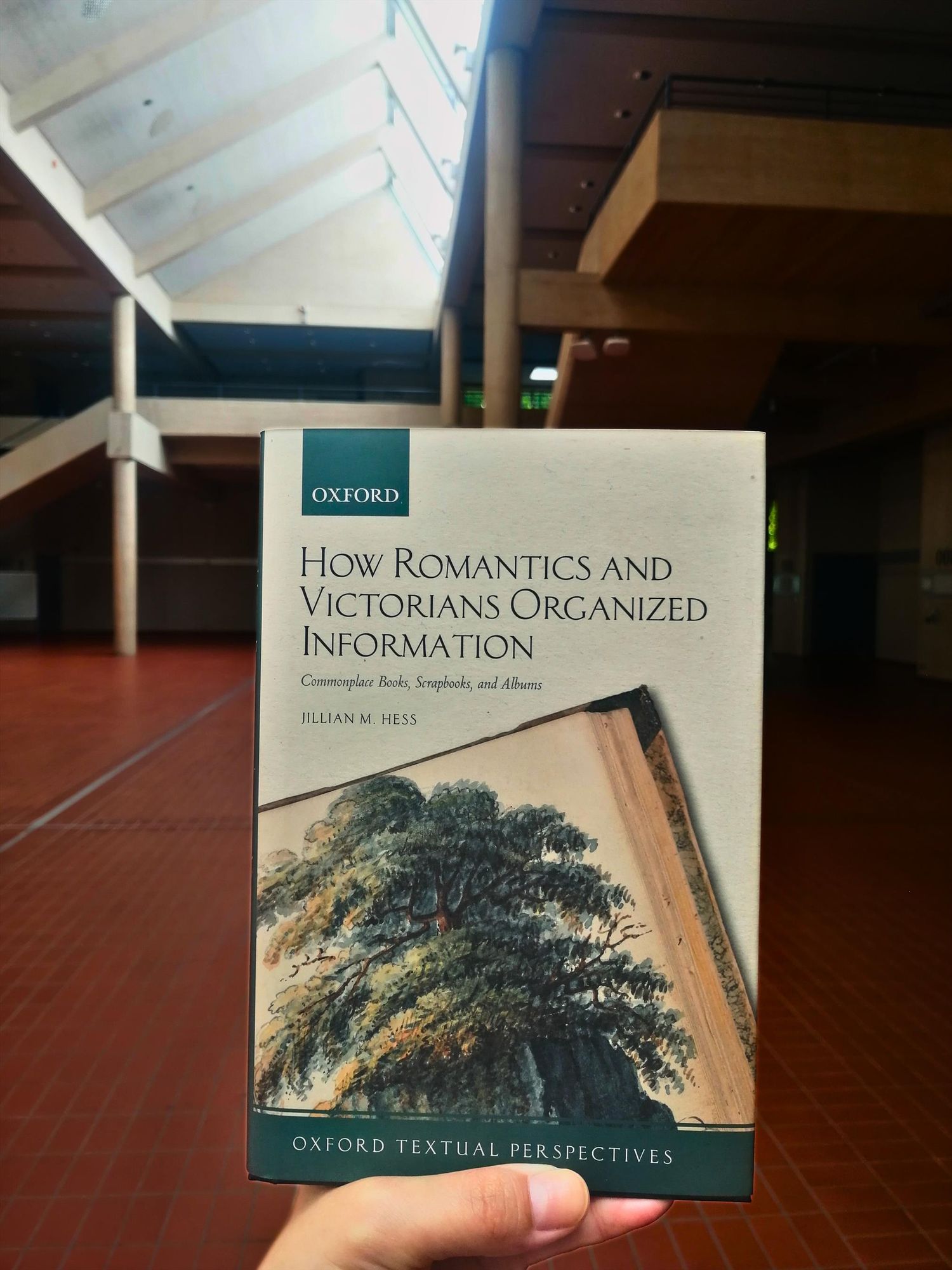 Holding the book "How Romantics and Victorians Organized Information" in the foyer of the University of Göttingen