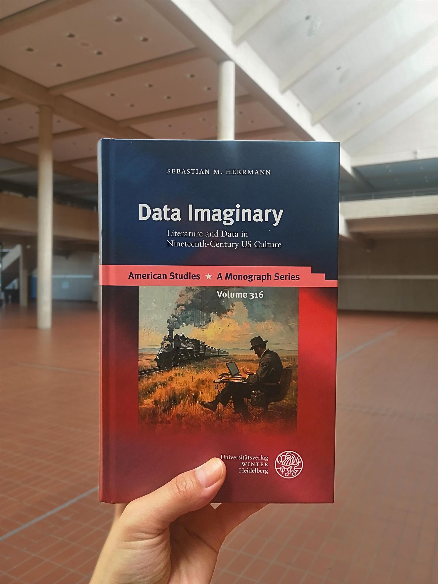 Holding the book "Data Imaginary" inside of the University of Göttingen's foyer