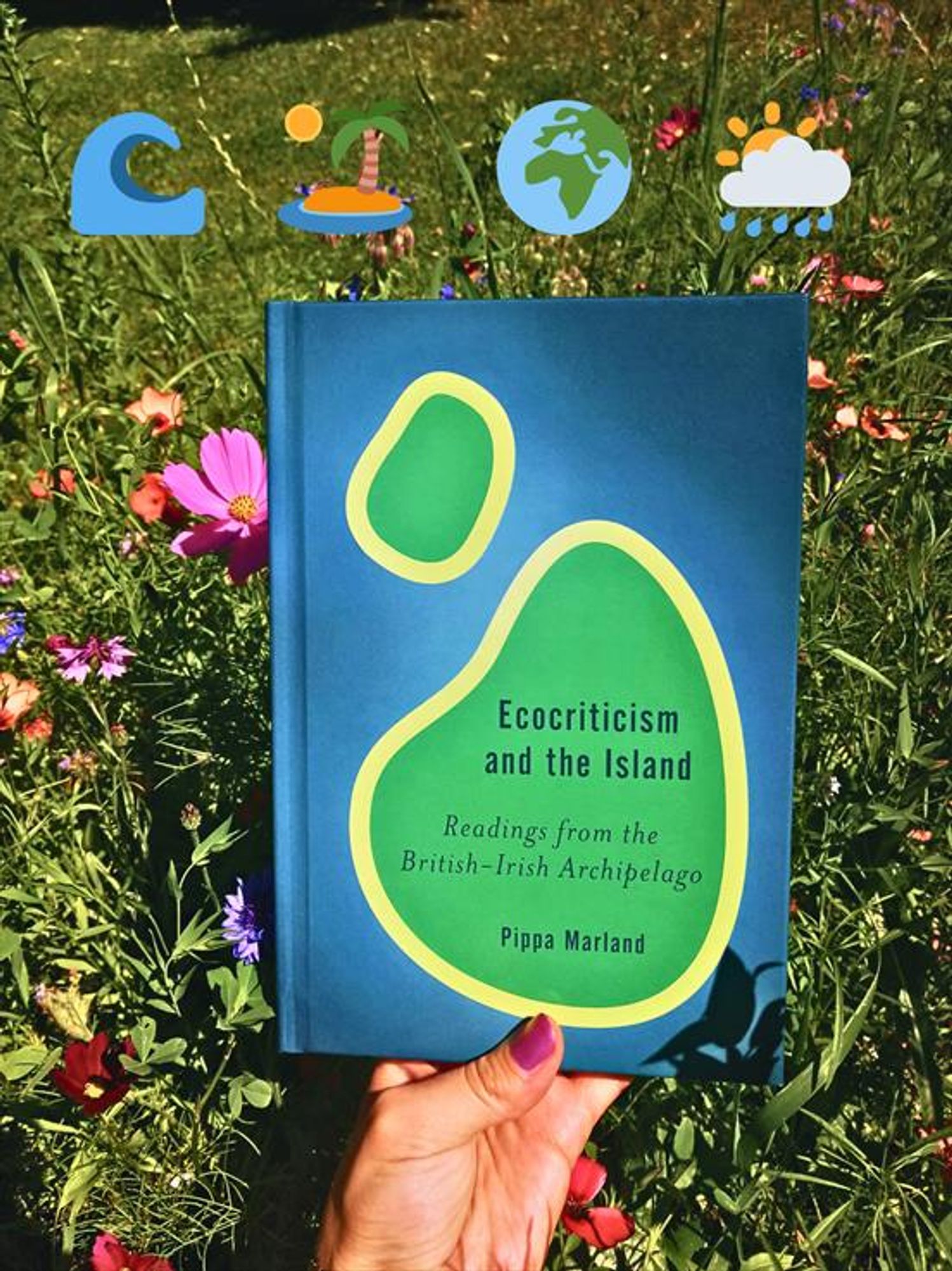 Holding the book "Ecocriticism and the Island" in front of a meadow with wildflowers. 4 emoji decorate the image: a wave, an island, the globe, zoomed in on Europe and Africa, and a rainy cloud behind which the sun is visible