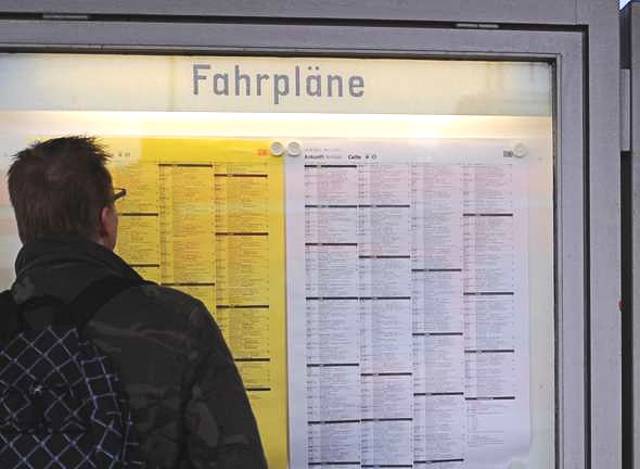 Eine Person, die vor dem Aushang der Fahrpläne der Deutschen Bahn steht.