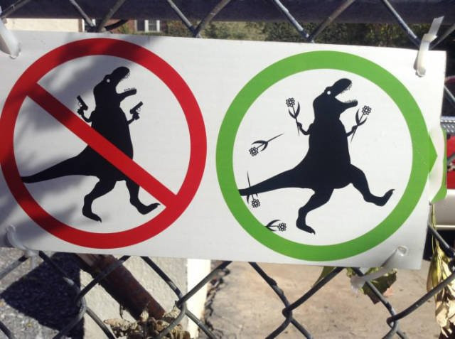 Links ein T-Rex Schild mit zwei Pistolen und rot durchgestrichen. Rechts daneben ein lachender T-Rex mit Blumen in der Hand. Grüner Ring um dieses Schild.