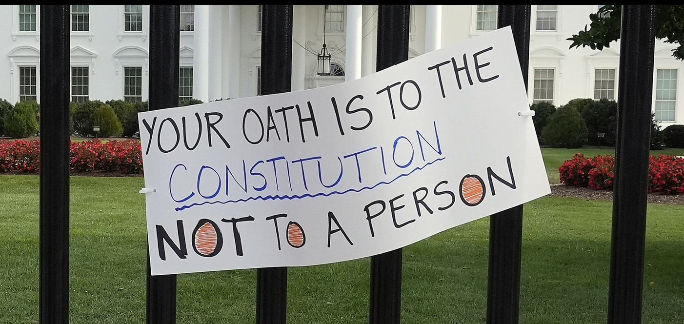 A sign hangs outside the White House as activists protest President Donald Trump’s federal takeover of policing of the District of Columbia, Saturday, Aug. 16, 2025, saying: Your Oath is to the Constitution; Not To a Person.