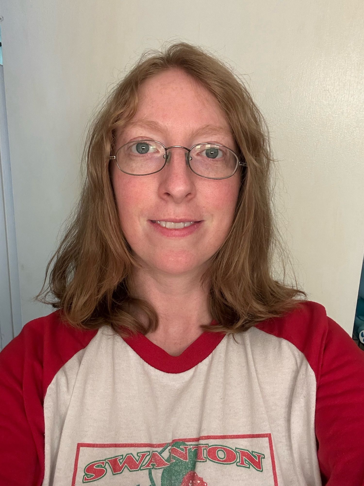 A real photo of a human woman with shoulder length hair and glasses, from the shoulders up.