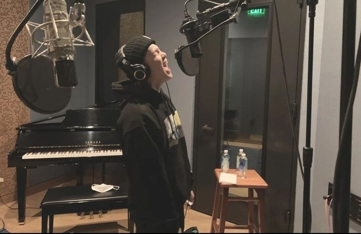 yoongi standing in front of a mic in a studio with his mouth wide open and his eyes closed, as if he was making a high note or screaming at the moment