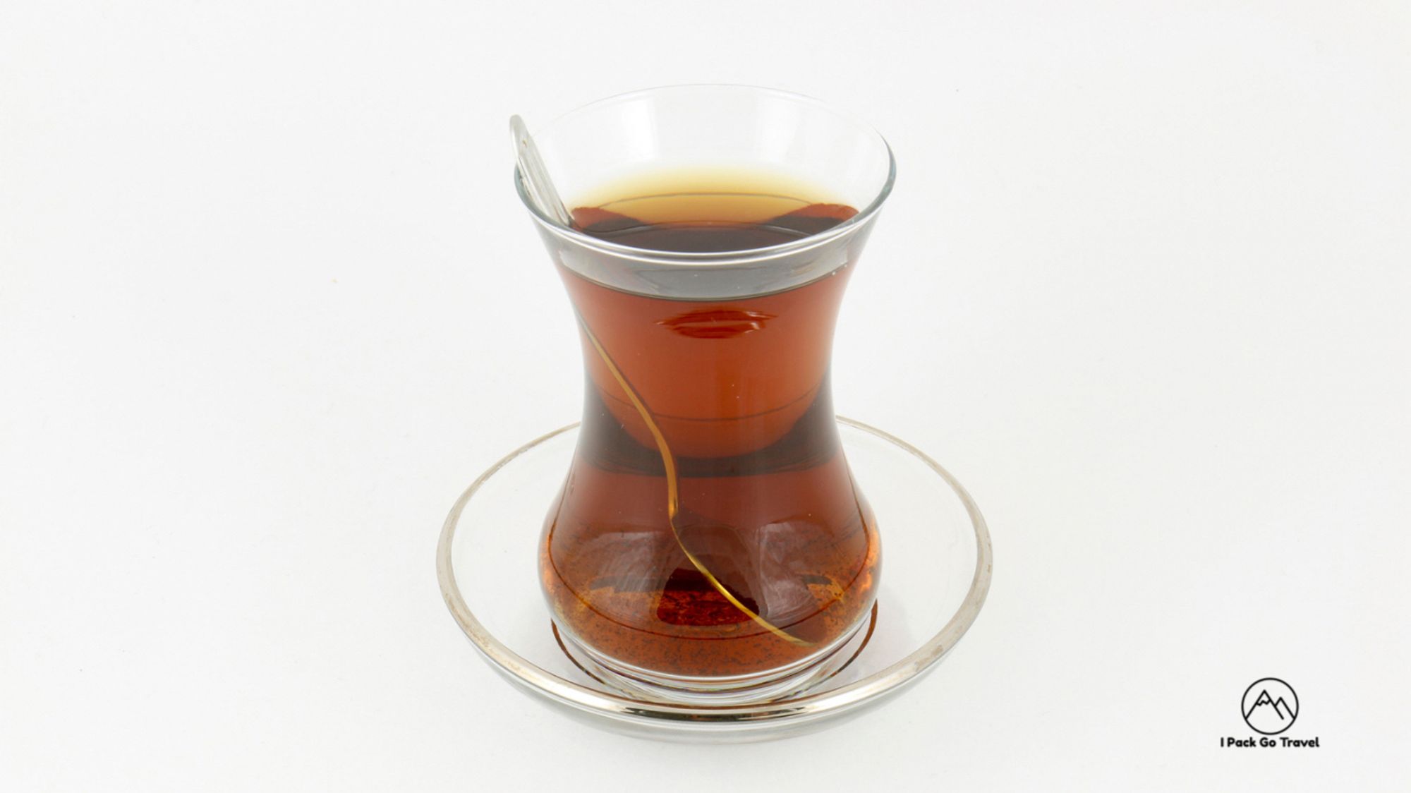 Tea in a glass cup and saucer. A teaspoon is visible in the cup.