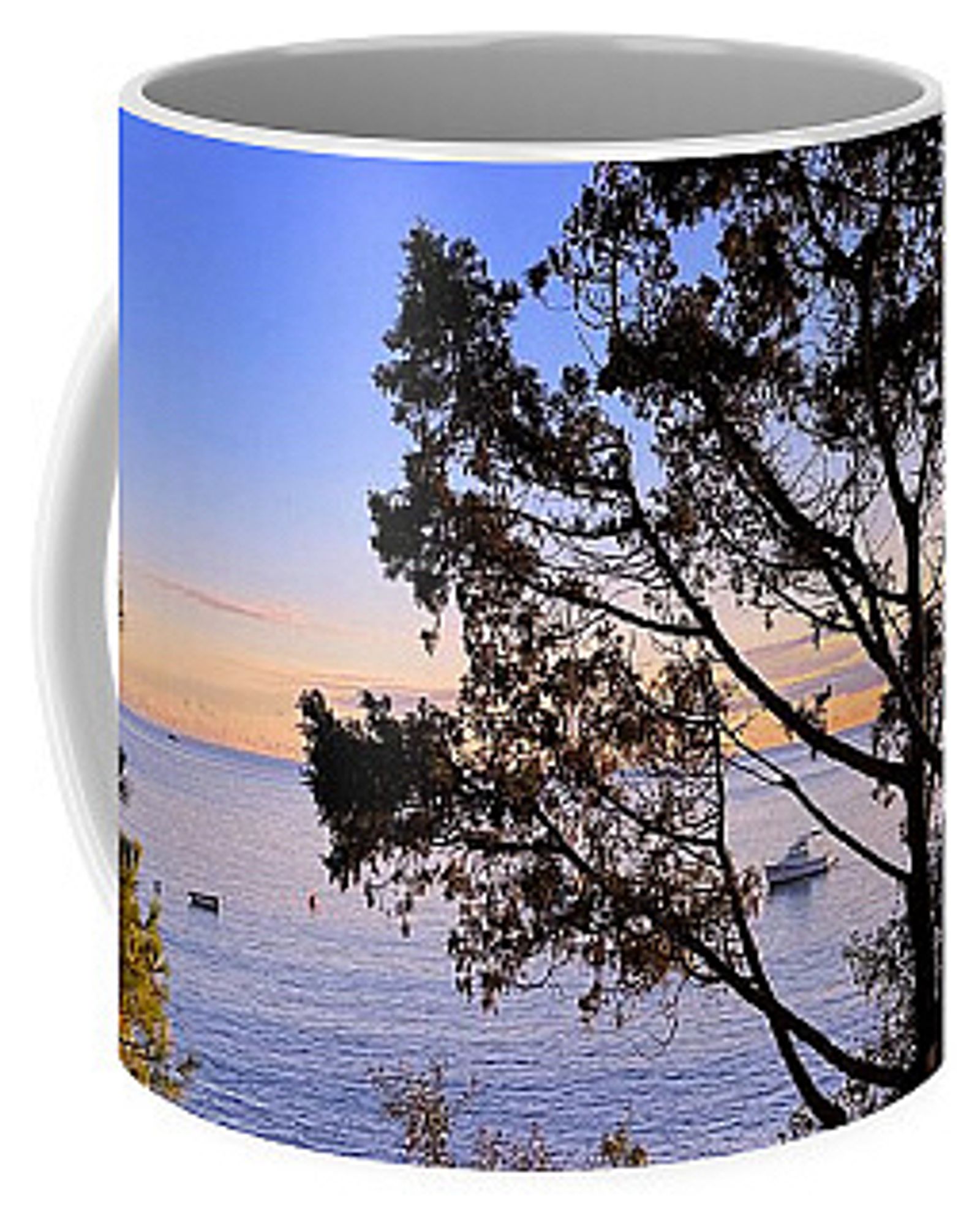 Coffee mug with the ocean, a floating boat, trees, pastel coloured clouds and blue sky in the background.