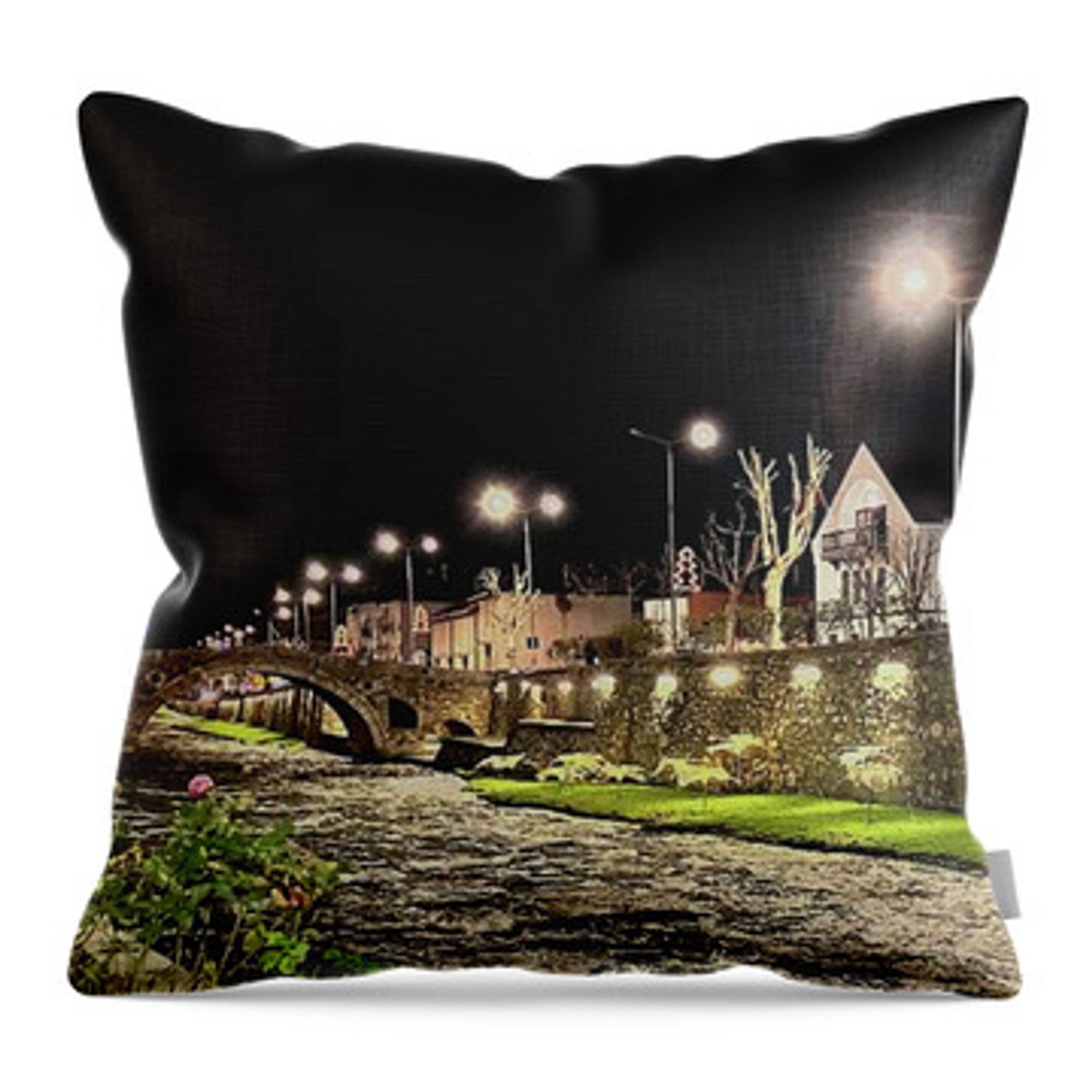 Throw pillow with art theme depicting a night scene of a river running through a city. There is a stone bridge and buildings on the embankment. The streetlights contribute to lighting up the area.