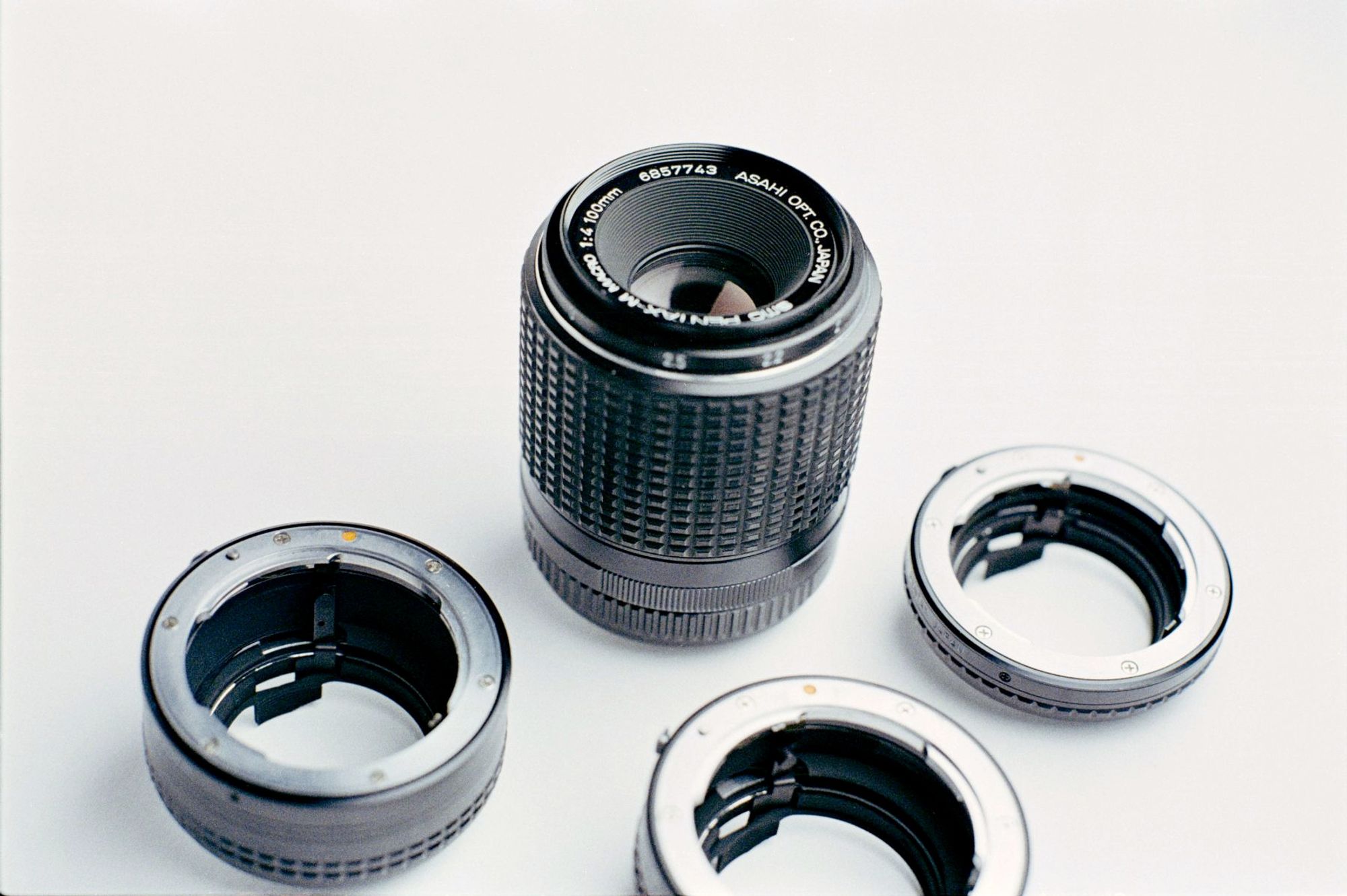 A 100mm full-frame lens with three extension tubes on a white background