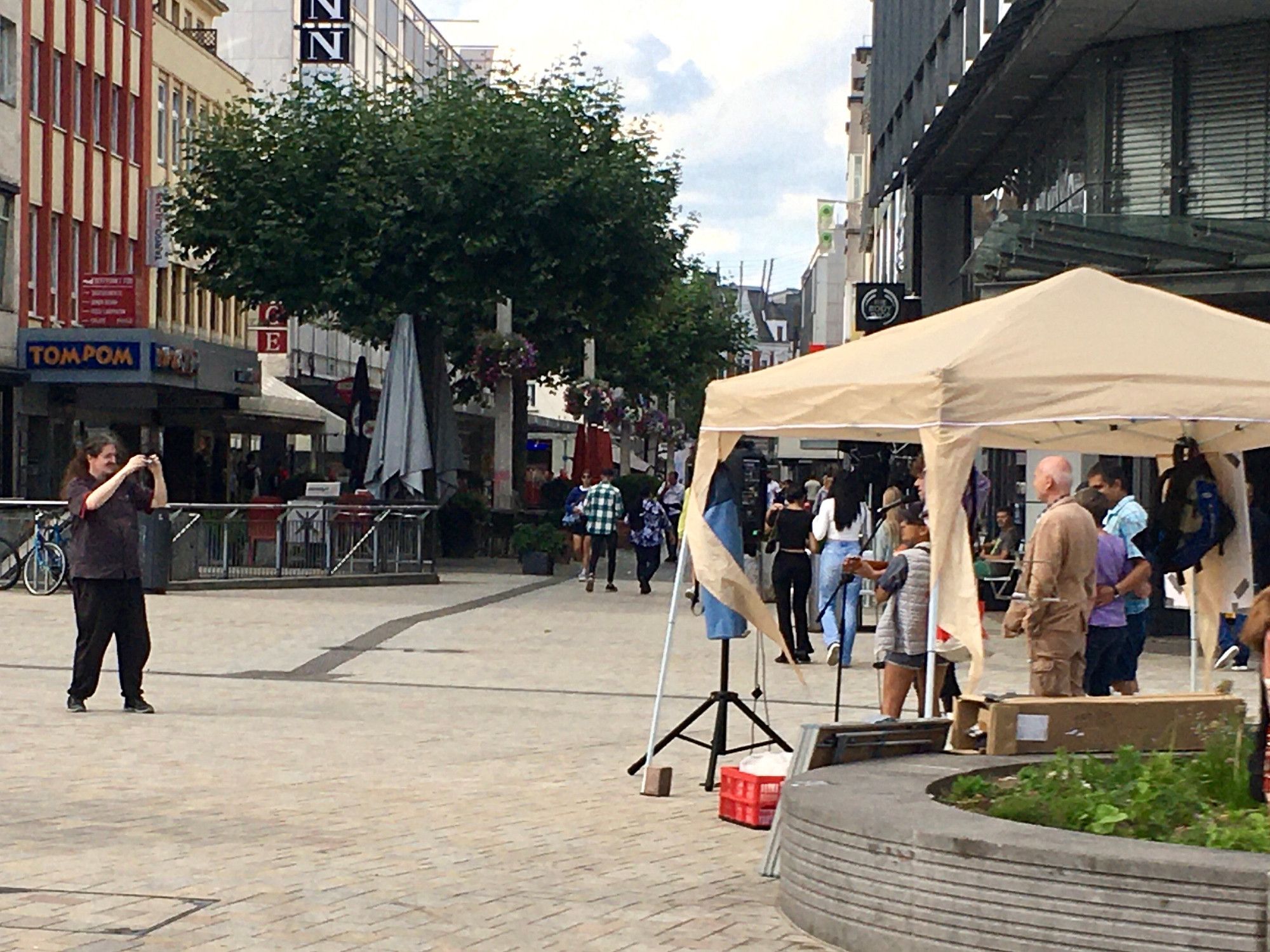 Ein Mann fotografiert einen Infostand mit einigen Leuten