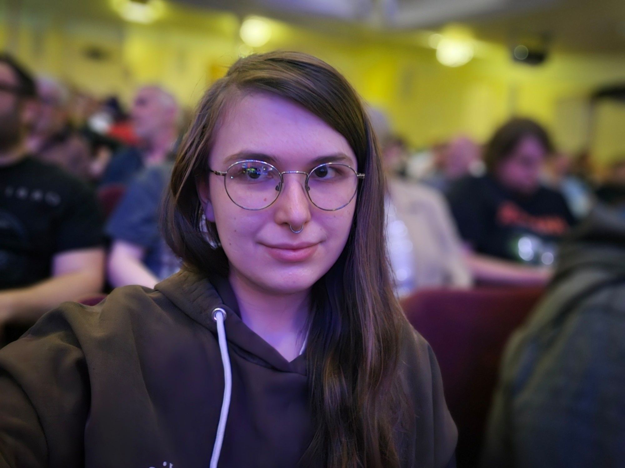 a selfie taken in a packed theater. wearing a brown hoodie with "dodie" queen on it