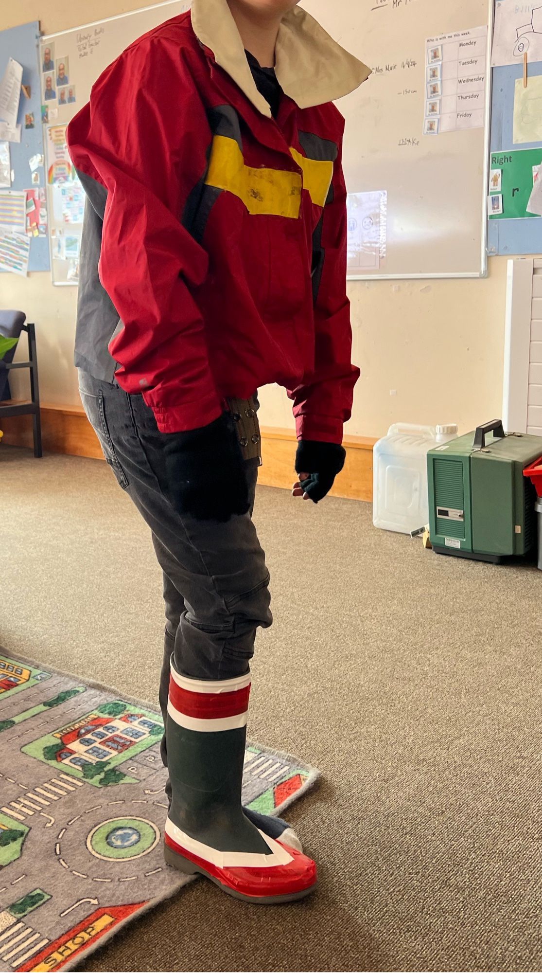 A young boy in a homemade Keith  costume. The boots are wellies with electrical tapes