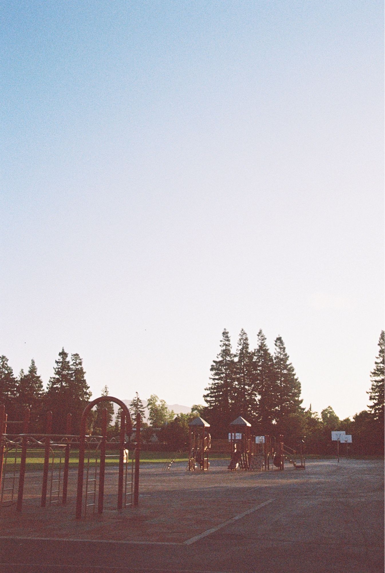 A play ground at dusk. The wide, white sky takes up the majority of the frame.