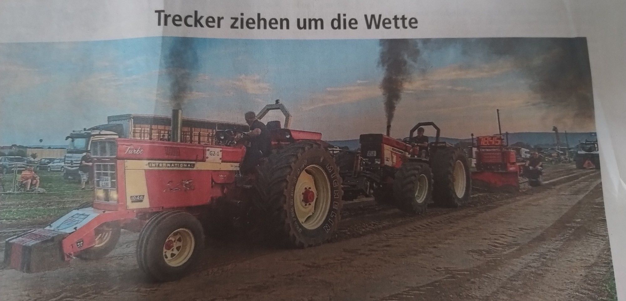 Zeitungsartikel:

Trecker ziehen um die Wette

Darunter ein Foto, das zwei Trecker hintereinander zeigt die ein schweres Gewicht zum Spaß ziehen und dabei vor blauen Himmel schwarze Abgaswolken in die Luft kosten.