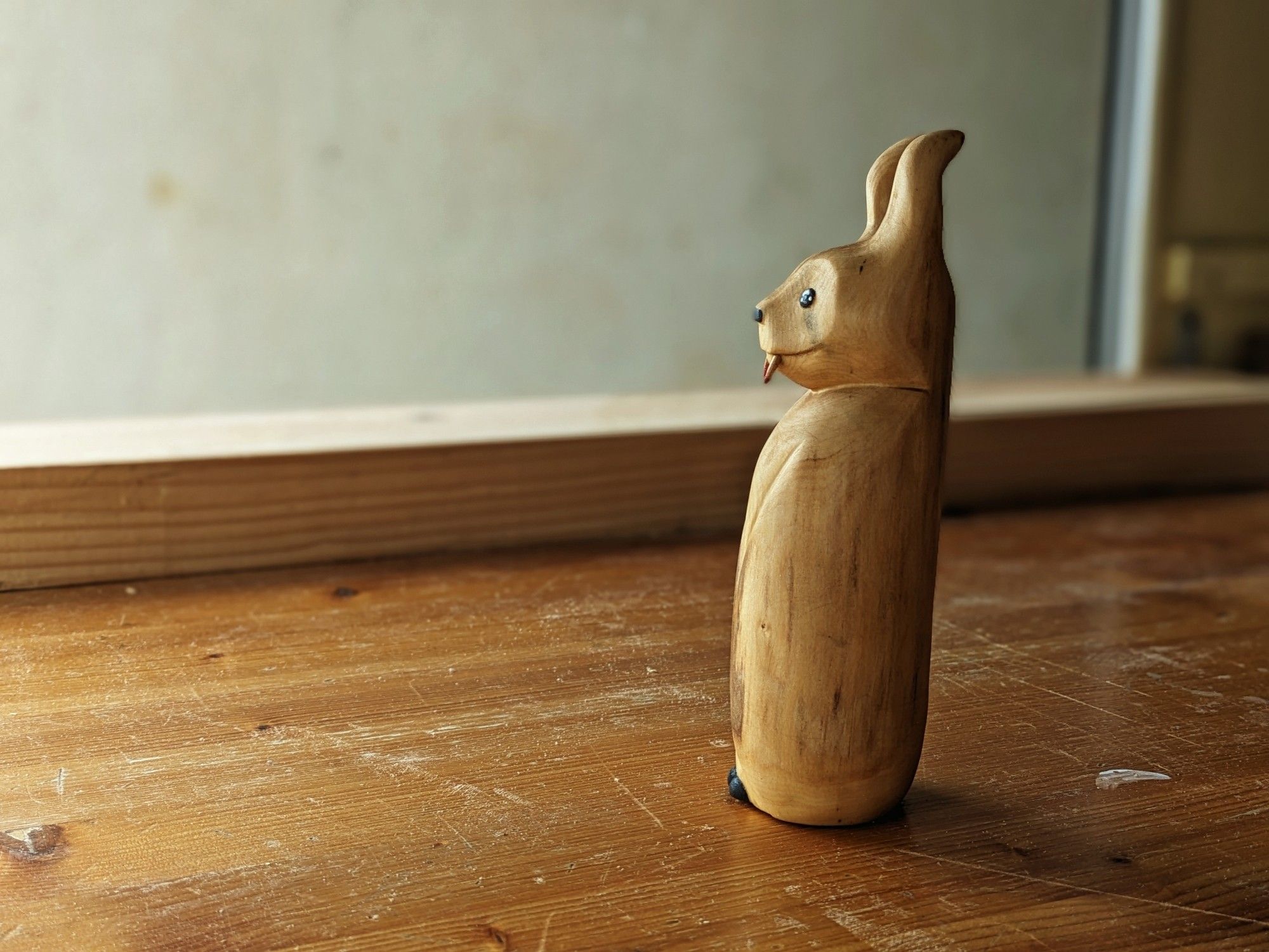 Woodcarved sculpture of a creature looking like a bat with horns