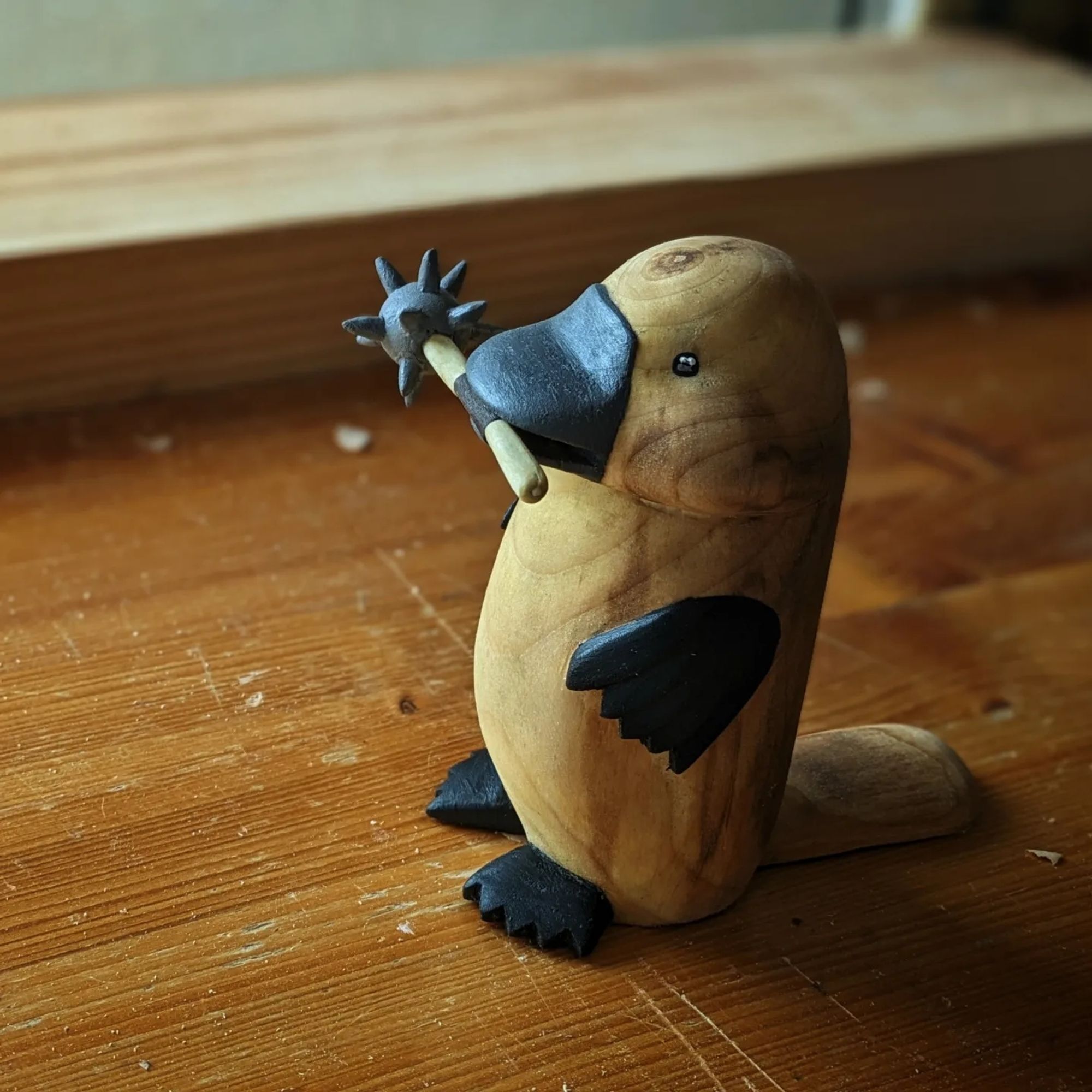 Woodcarved standing platypus with a morgenstern in its beak