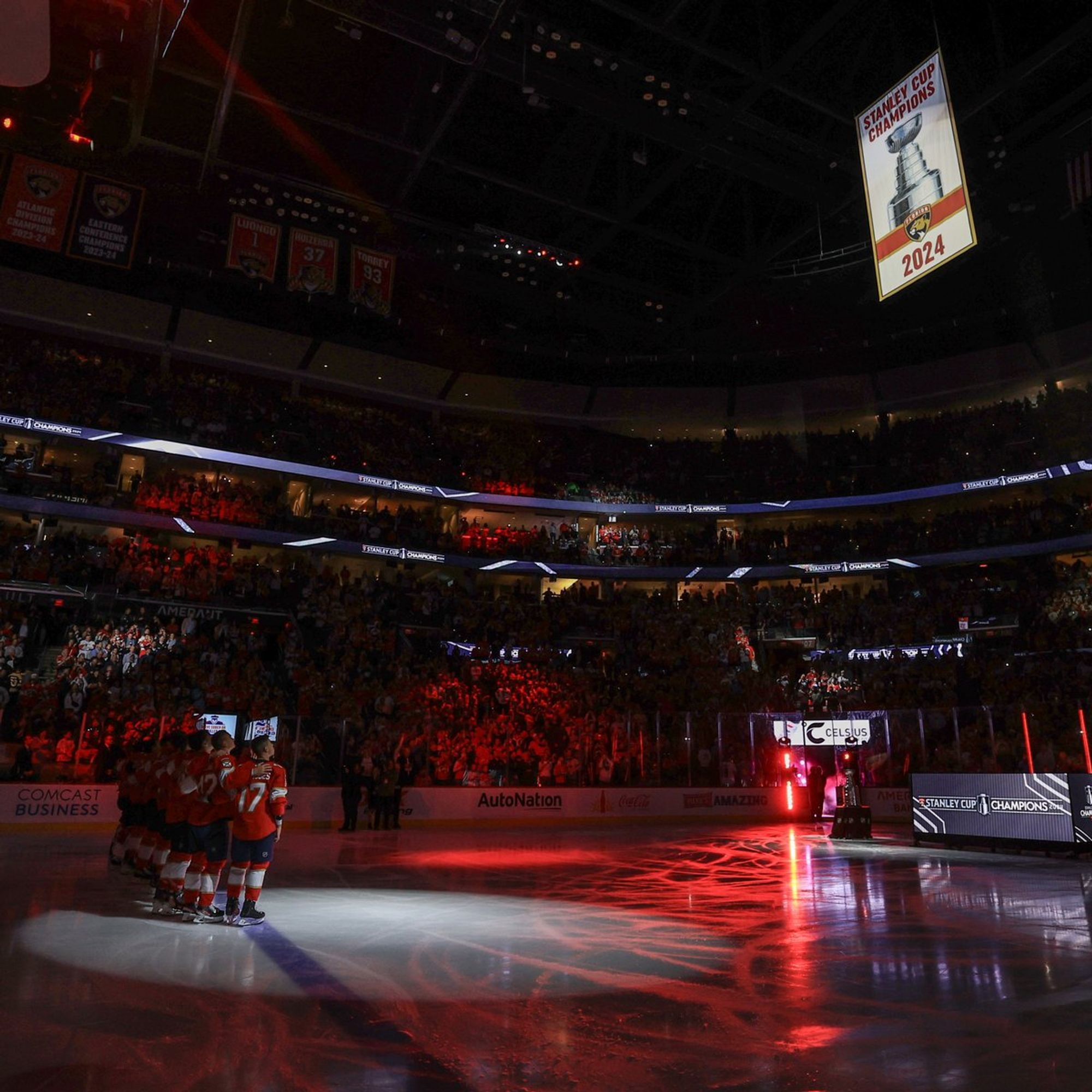 Photo of Florida Panthers players looking on as their Stanley Cup championship banner is raised.