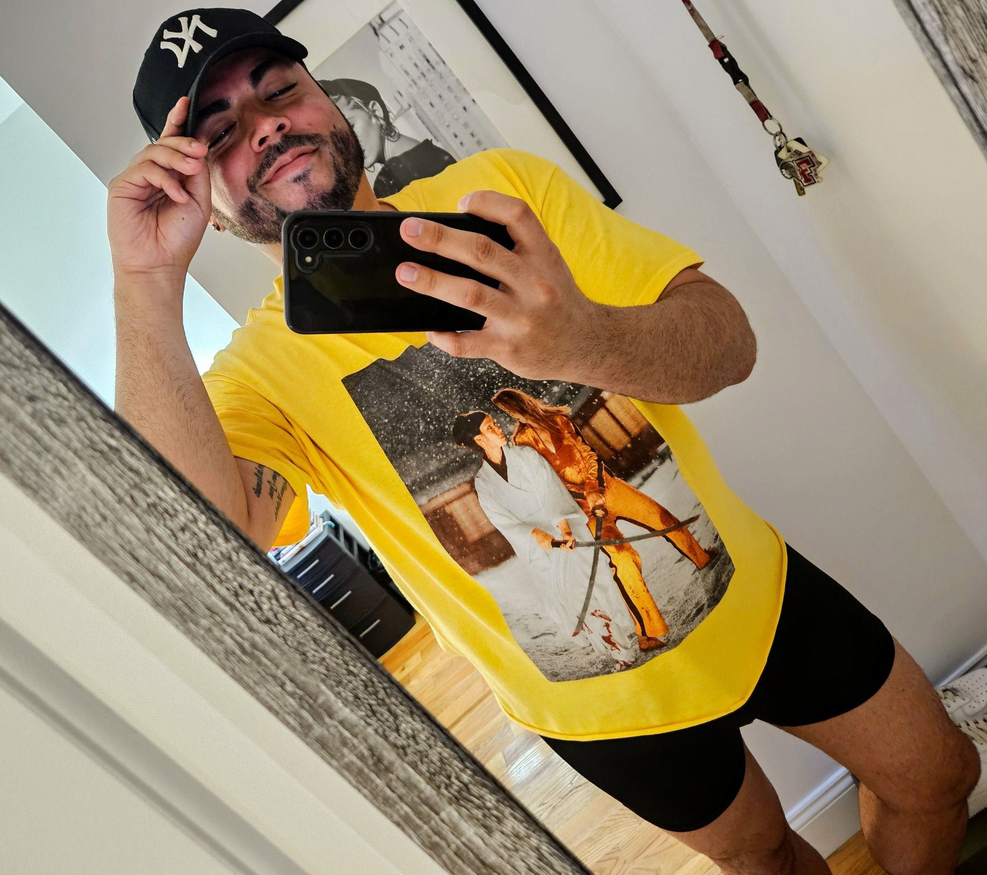 A mirror selfie of a mid-30's Puerto Rican male in a yellow Kill Bill t-shirt, a black Yankee hat, and boxers briefs.