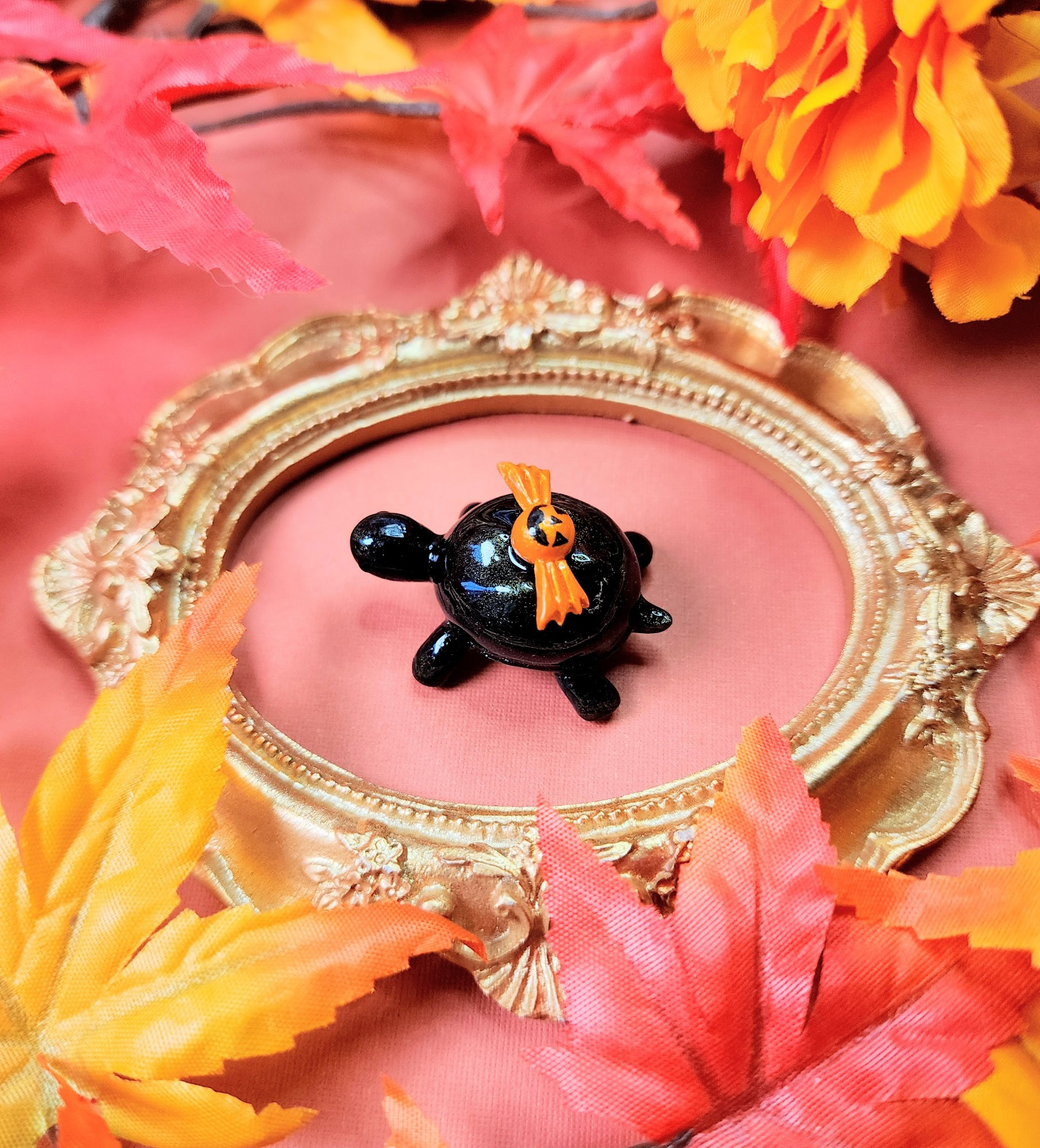 A little black turtle figure based off of over the garden wall. It has a little orange candy on its back with a jack-o-lanturn face on it.