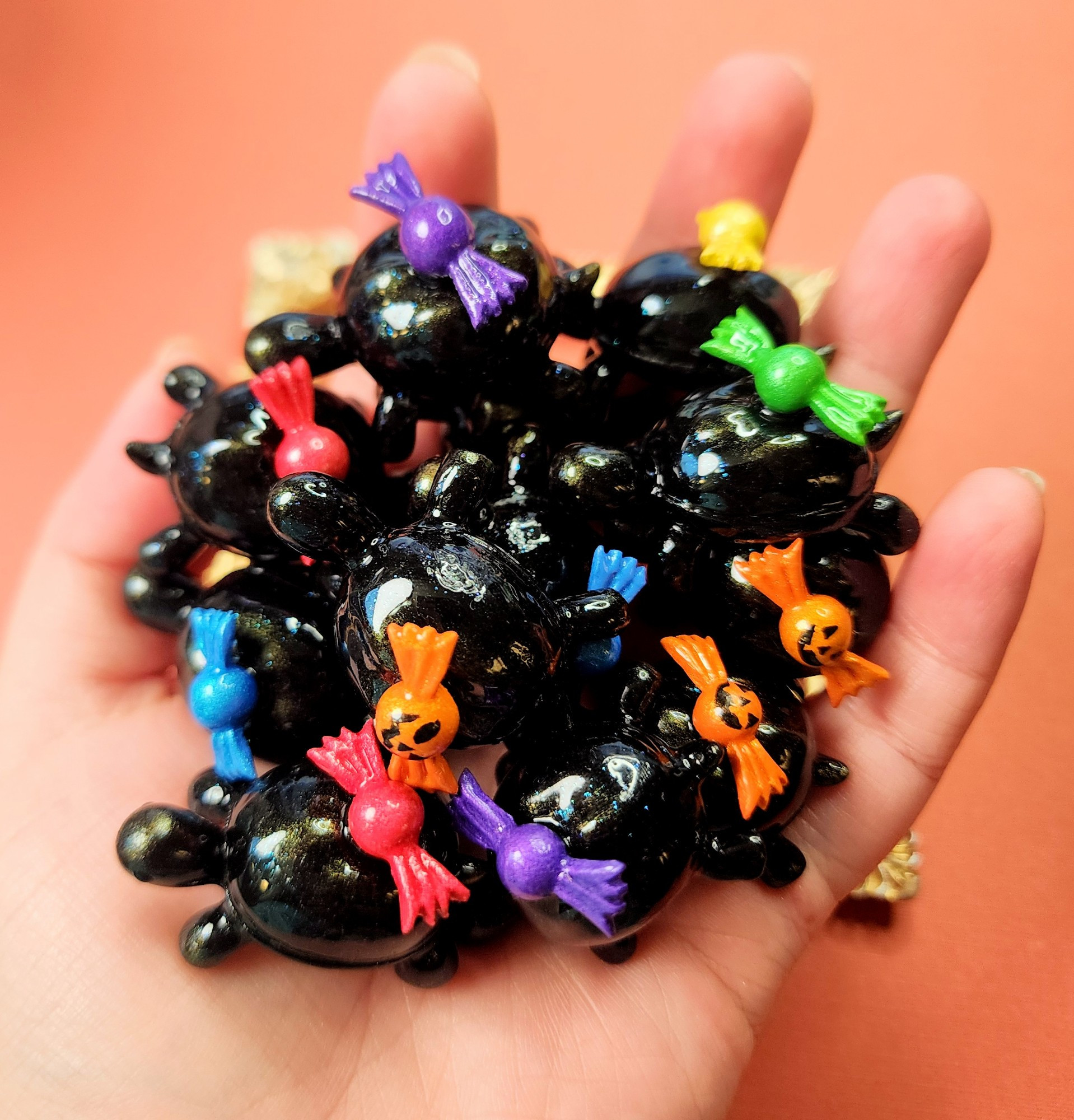 Little black turtle figures in a pile in a hand based off of over the garden wall. Each turtle has a random colored candy on their back like the show.