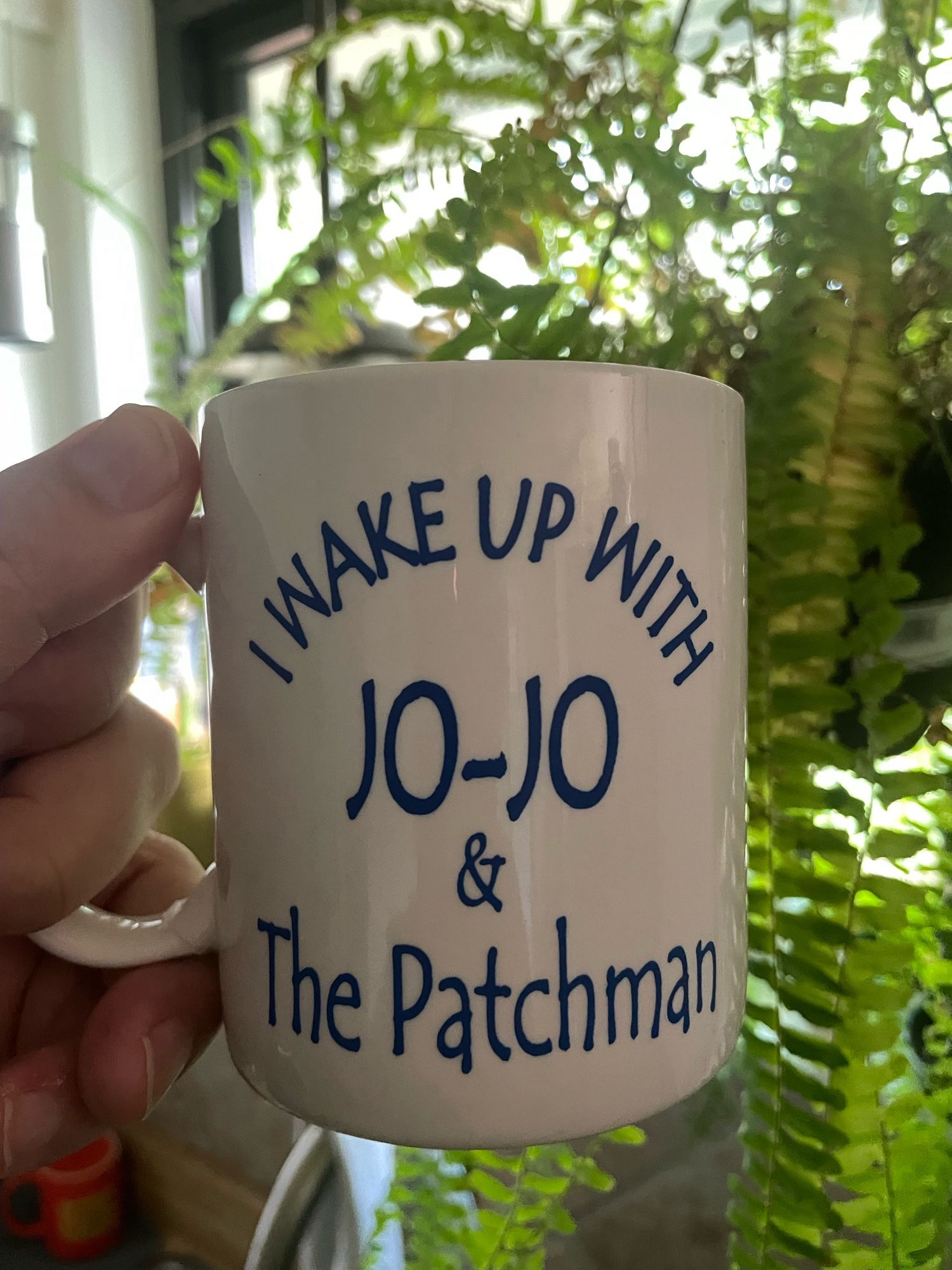 A white coffee mug. It says “I wake up with Jo-Jo & The Patchman”