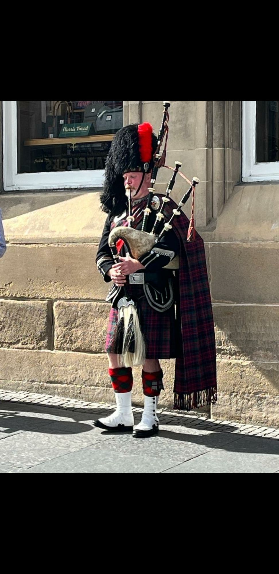 Man in a kilt and big black hat playing bagpipes