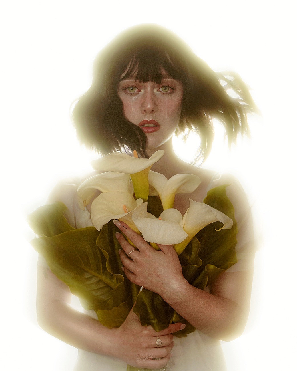 Short-haired woman in the wind with a bouquet of calla lilies in her hands while two tears fall down her face