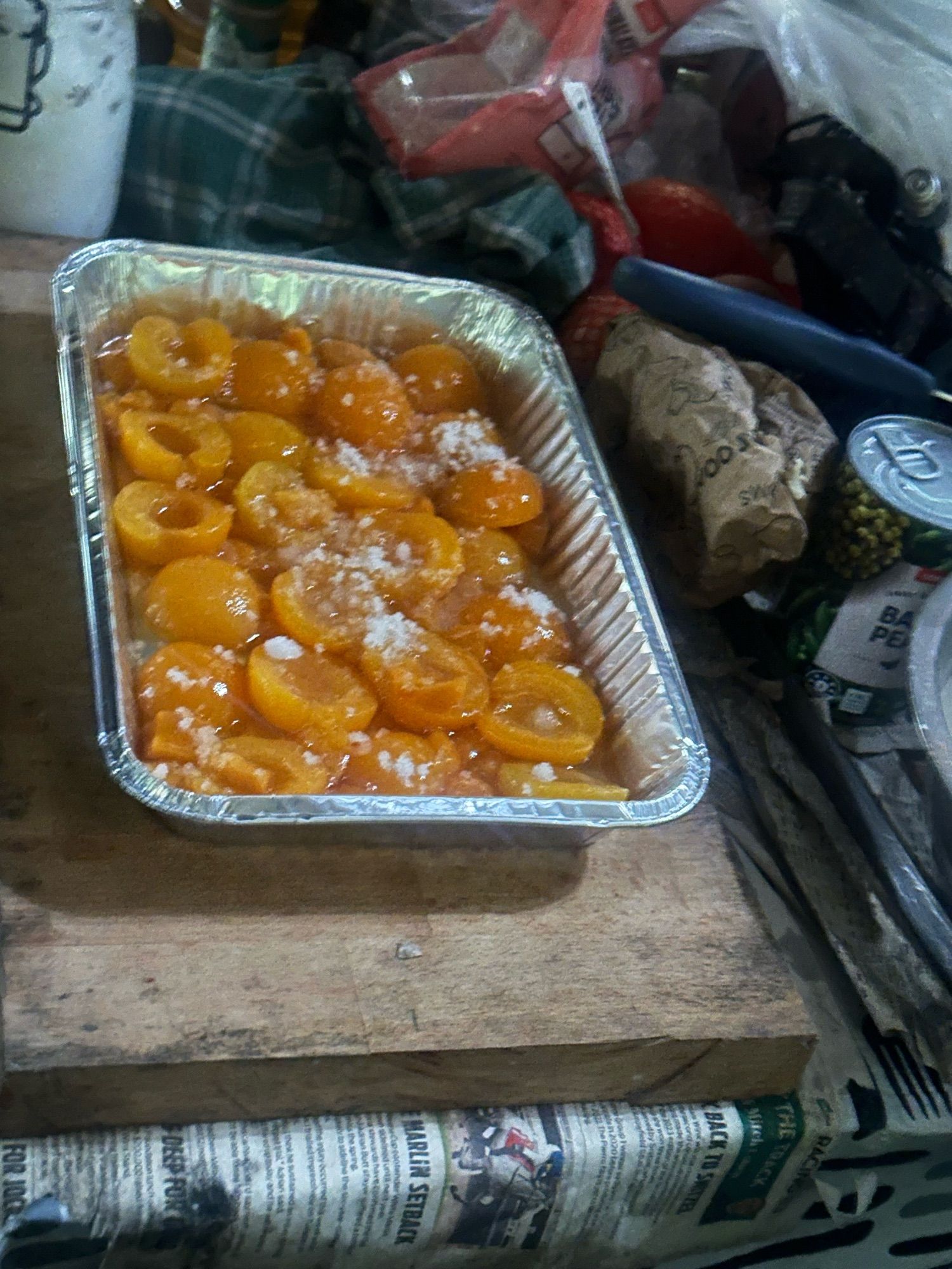 Peaches in a large tray prepping for a peach pie on a wood board