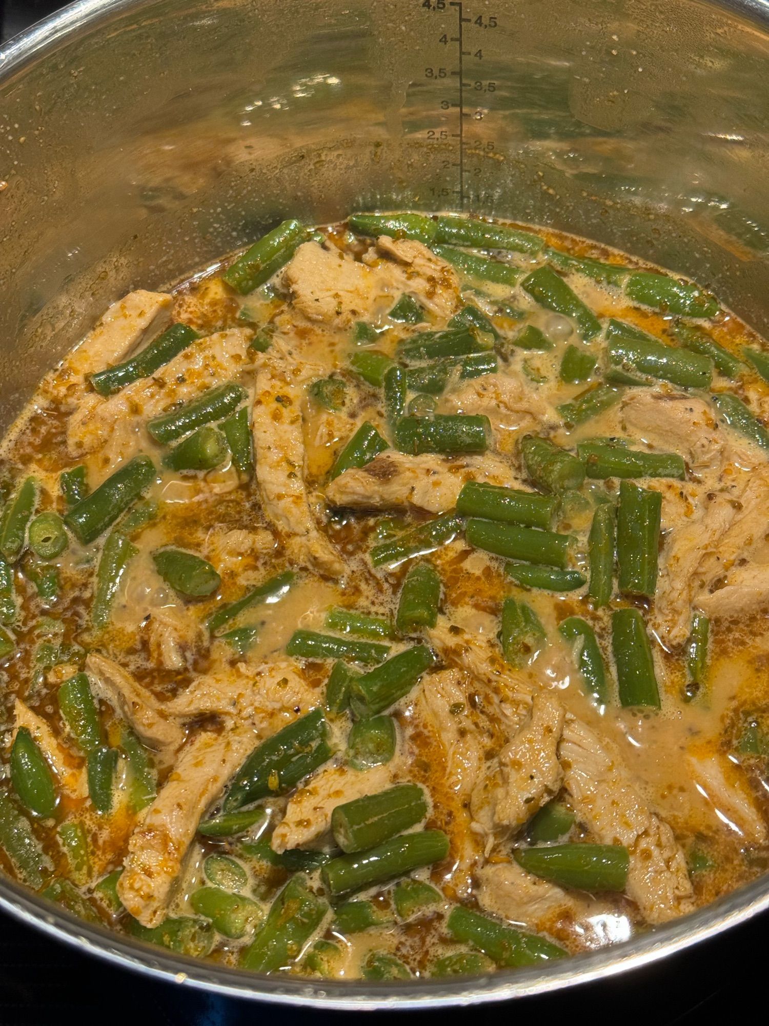 Pot filled with green beans and chicken in spicy sauce