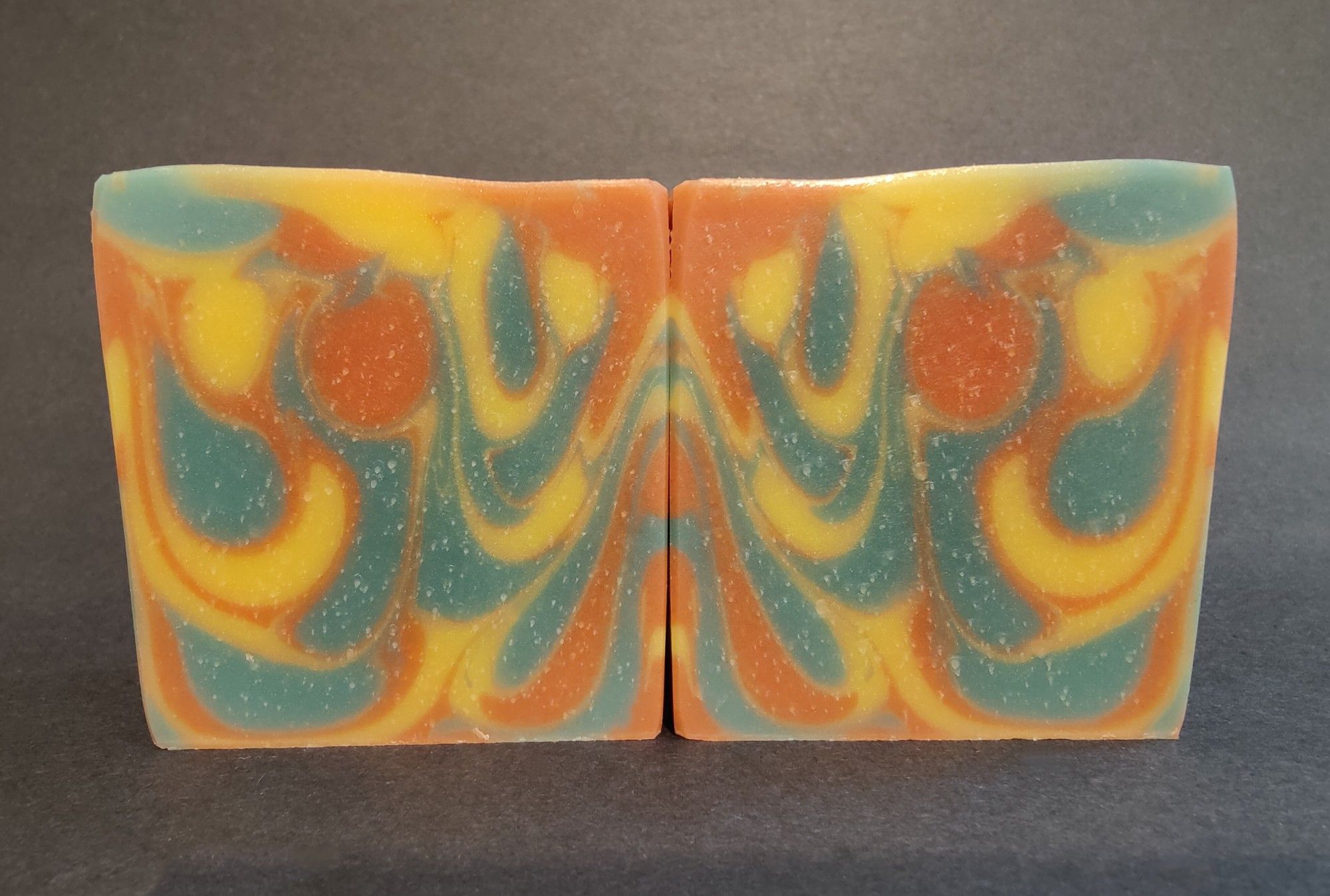 Two bars of green, yellow and orange soaps sitting next to each other showing an inkblot like design