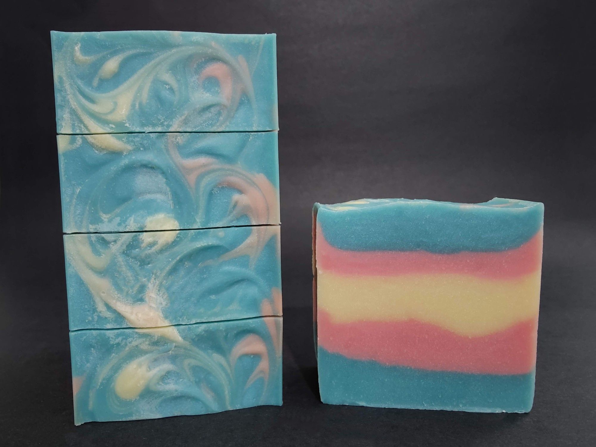 Soaps colored with the Trans Pride flag colors with a swirl pattern on top. They are blueberry scented