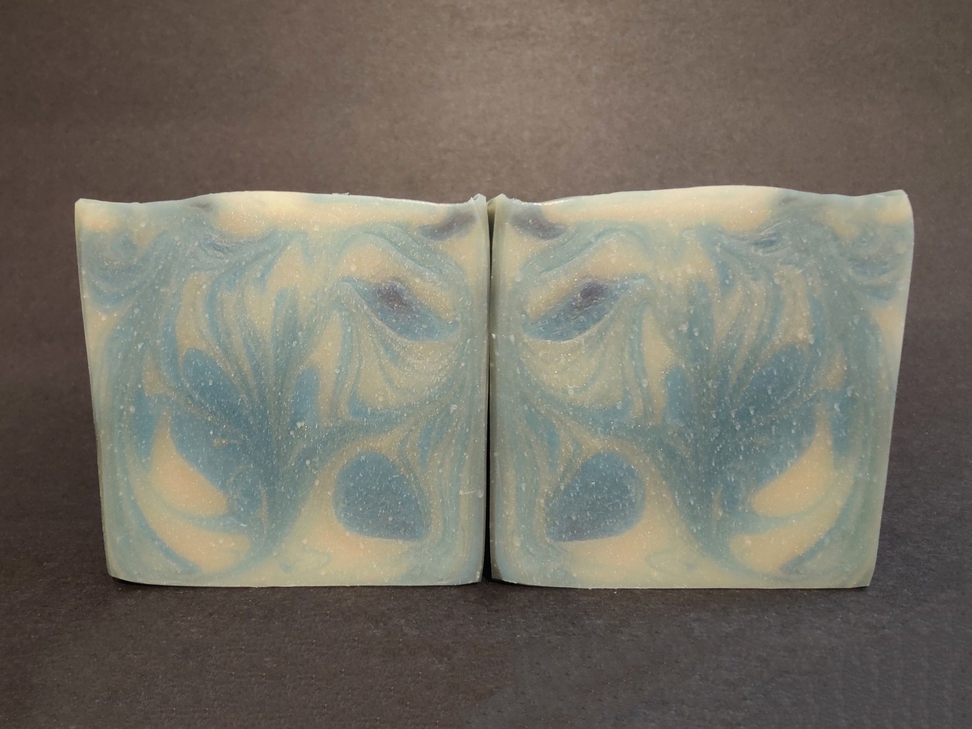 Two blue and white soaps are sitting side by side to show their swirls