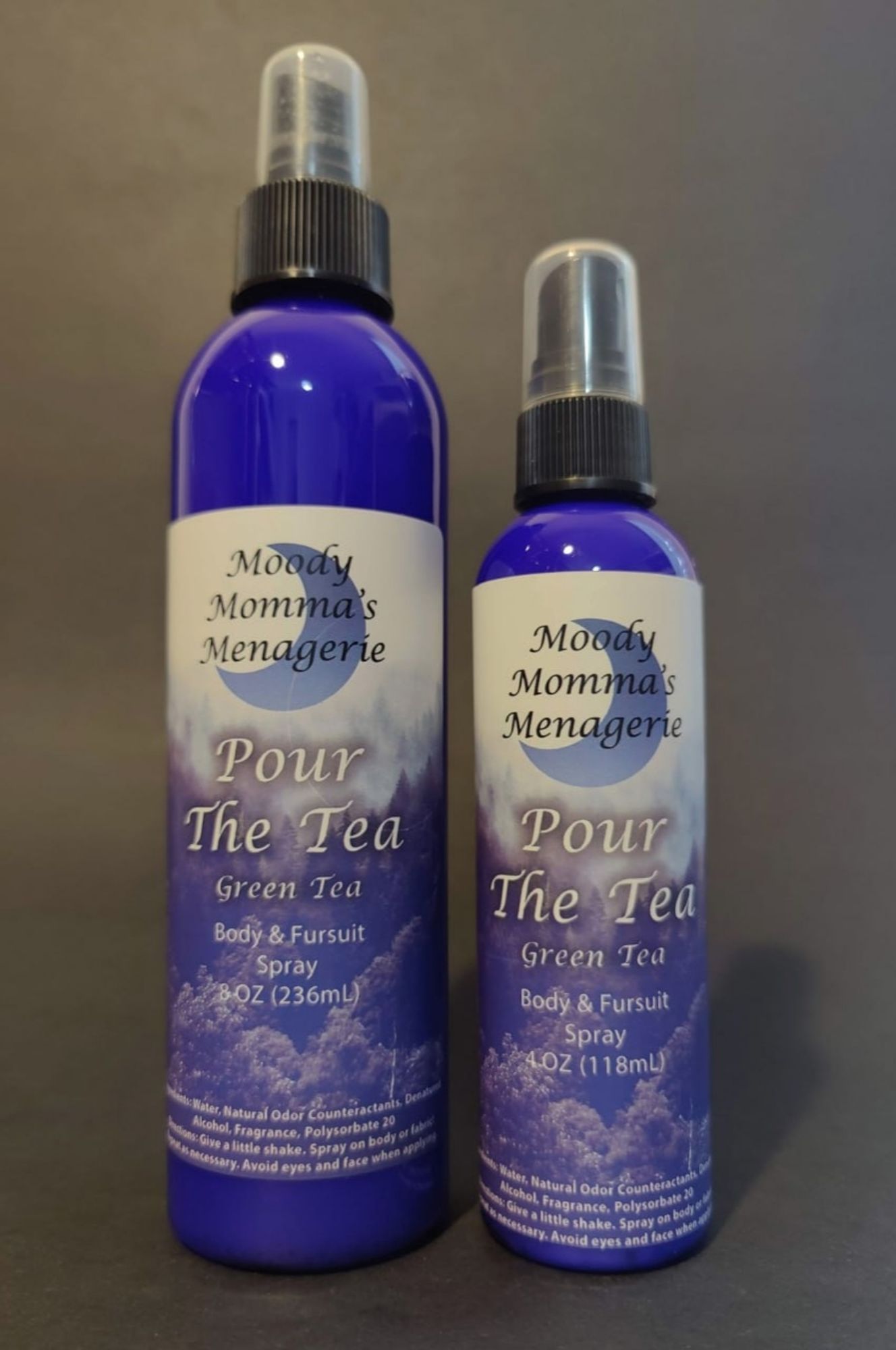 An 8 ounce blue bottle and a 4 ounce blue bottle of body/fabric spray in the fragrance Pour The Tea. The fragrance notes are Green Tea