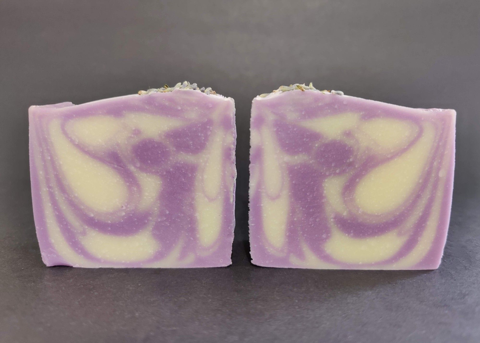 Two bars of purple and white lavender soaps sitting next to each other