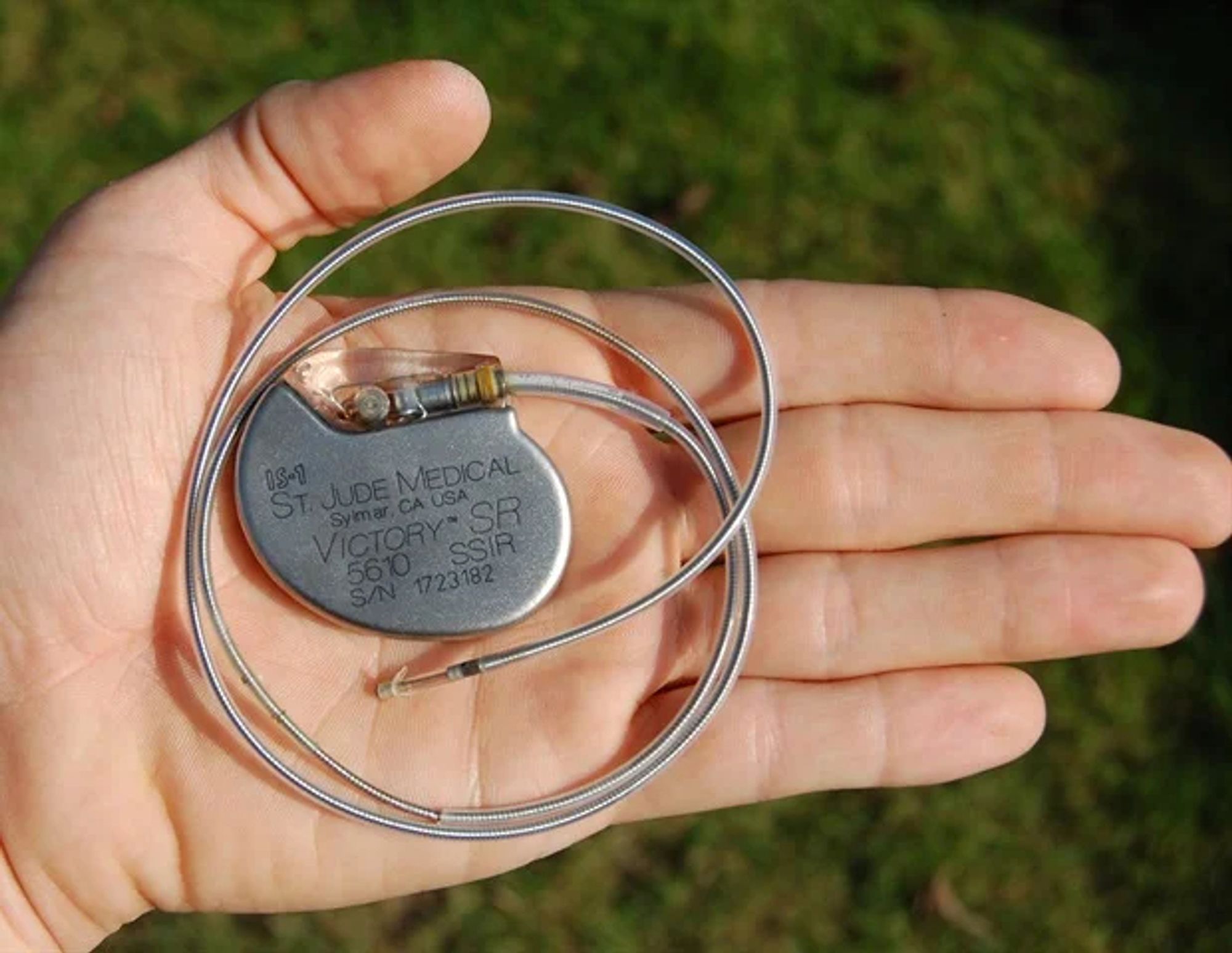 A metal pacemaker with cord (in the palm of a person's hand).